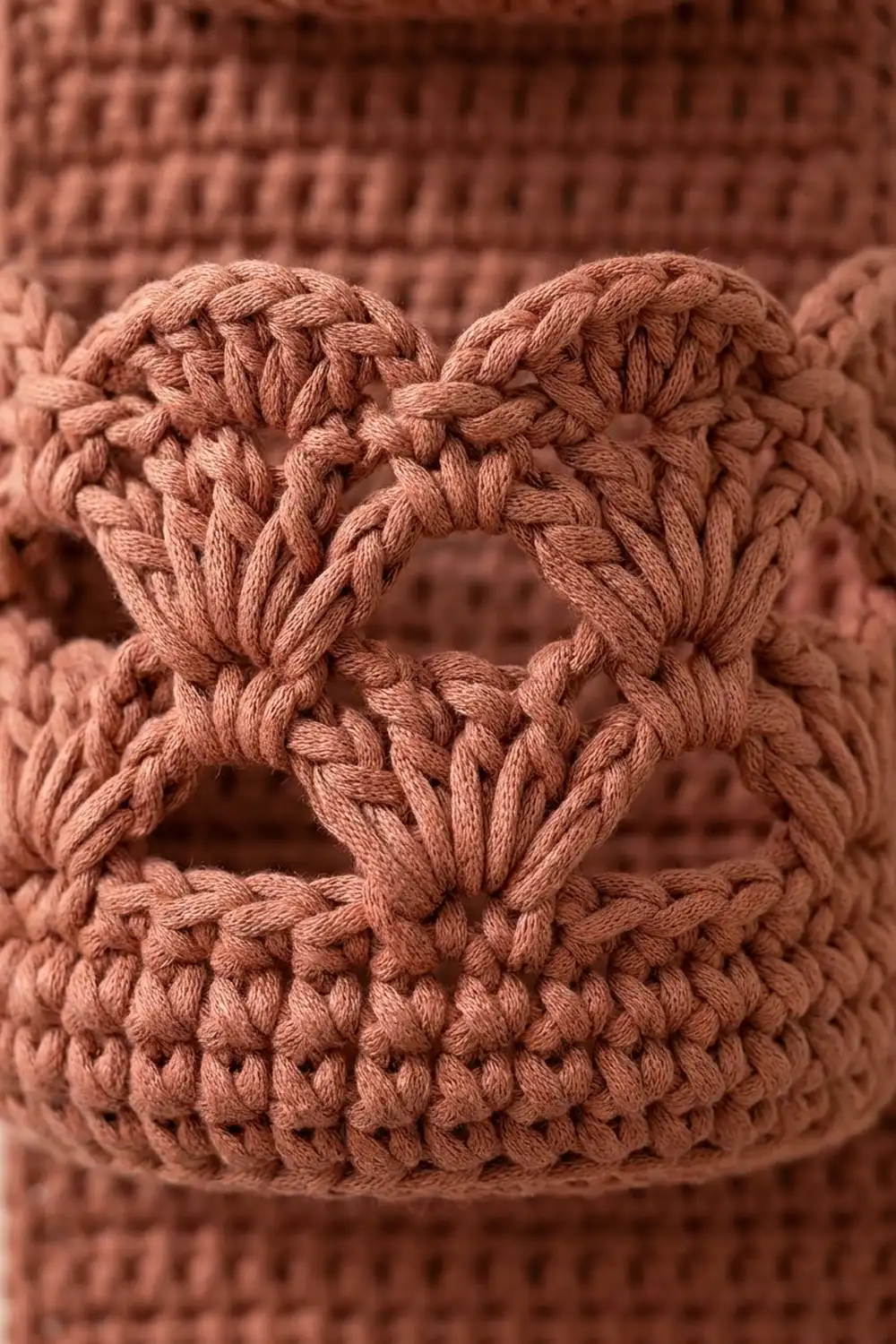 Tan crochet fabric with detailed, dimensional stitch patterns creating textured geometric relief.