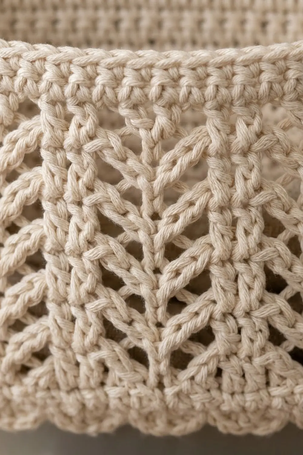 Close-up detail of cream-colored crochet lace showing an intricate openwork pattern with diamond stitches.