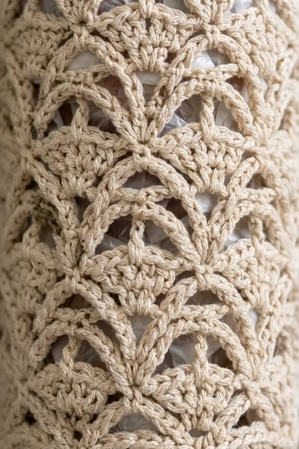 Close-up of cream-colored crocheted lace fabric with intricate diamond-shaped openwork pattern.