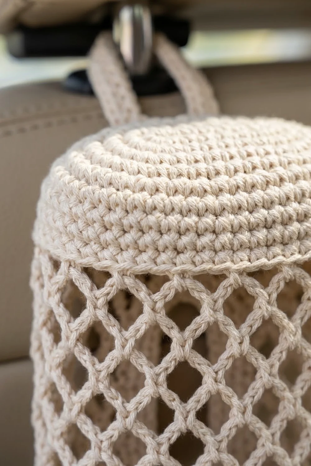 Cream-colored crocheted fabric with dense textured stitches above an open lattice pattern, displayed with crochet hooks in soft focus behind.