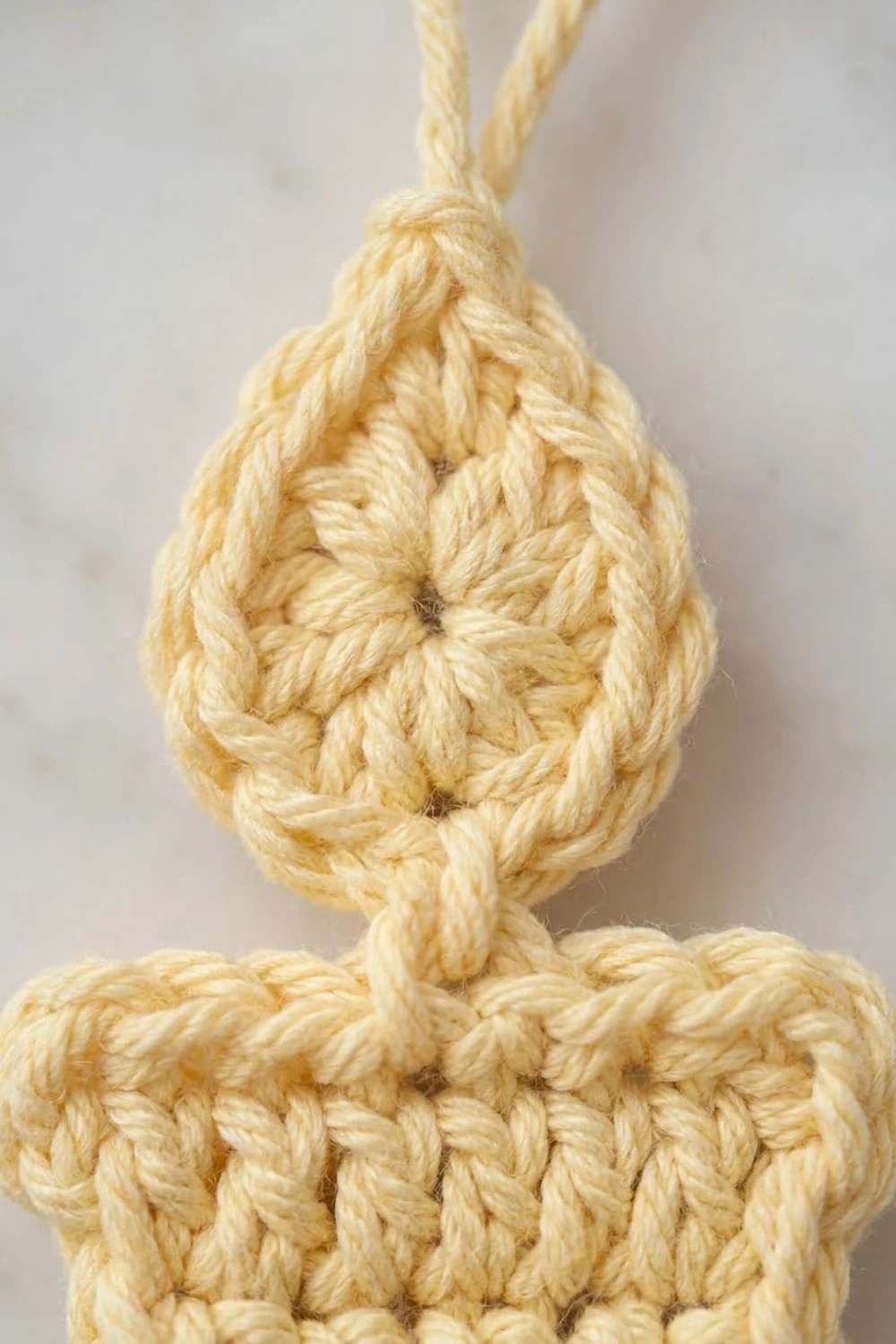 Close-up of a natural jute rope knot with a teardrop loop and rectangular base against a neutral background.