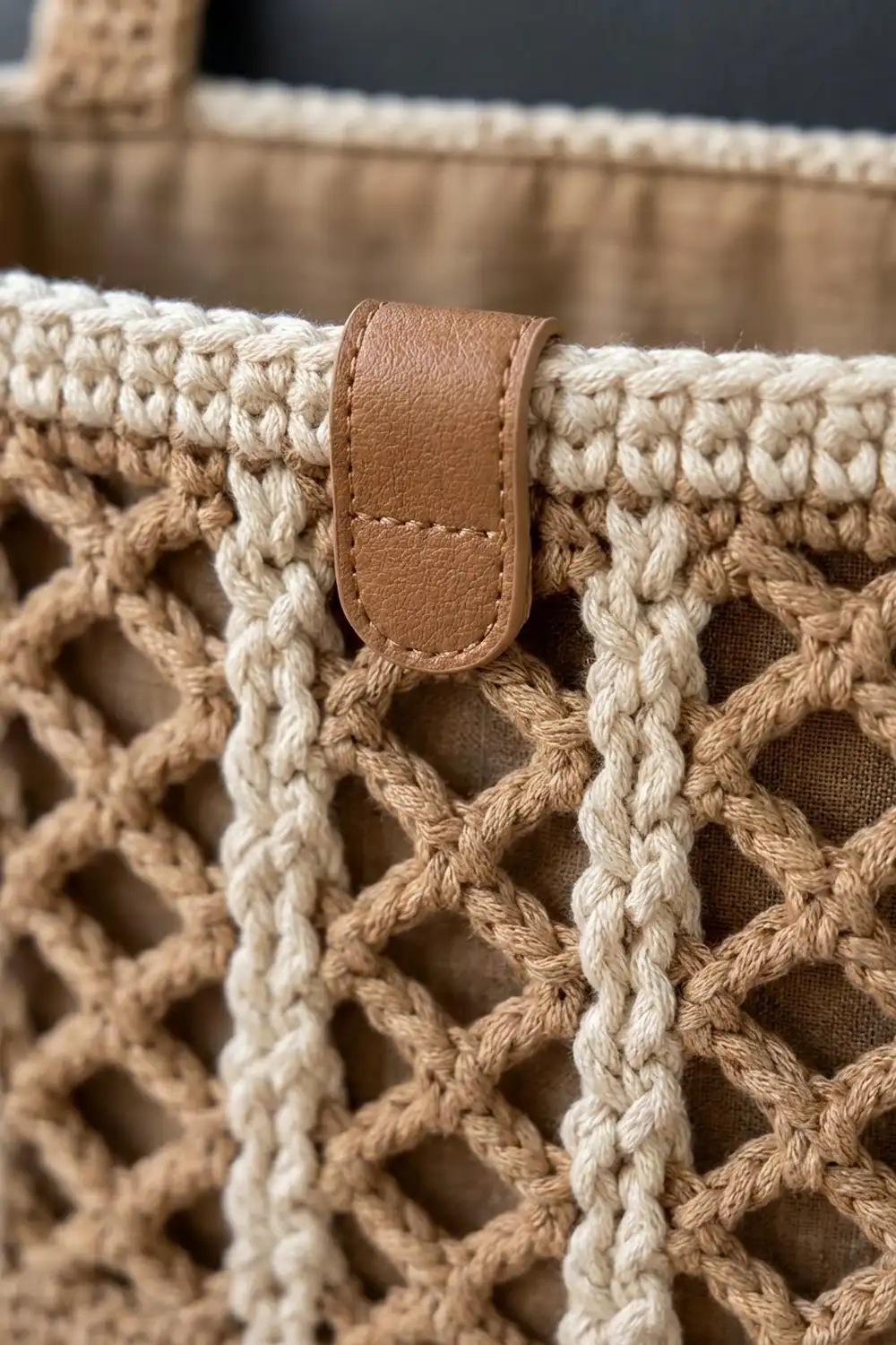 Tan crocheted fabric with geometric mesh pattern features a brown leather label tab sewn into the weave.
