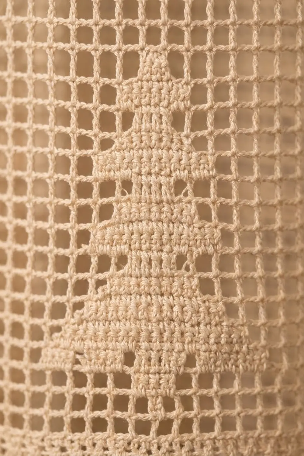 Cream-colored crochet with open-lattice mesh and a densely stitched decorative center motif.