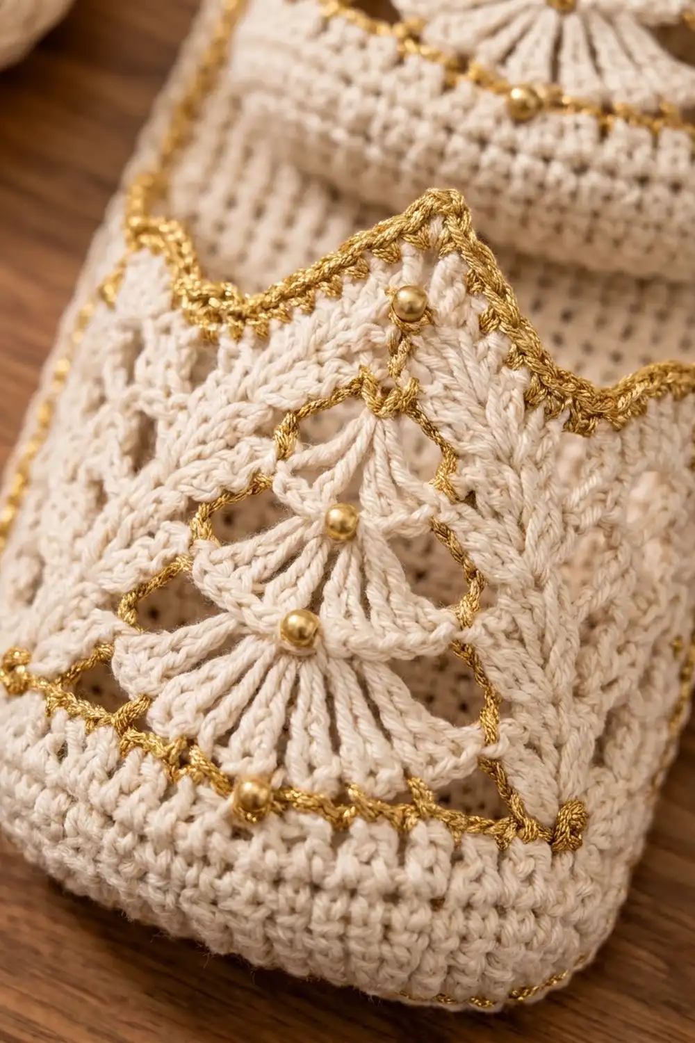 Cream-colored crocheted fabric with delicate scalloped edge trimmed in gold thread and beads.