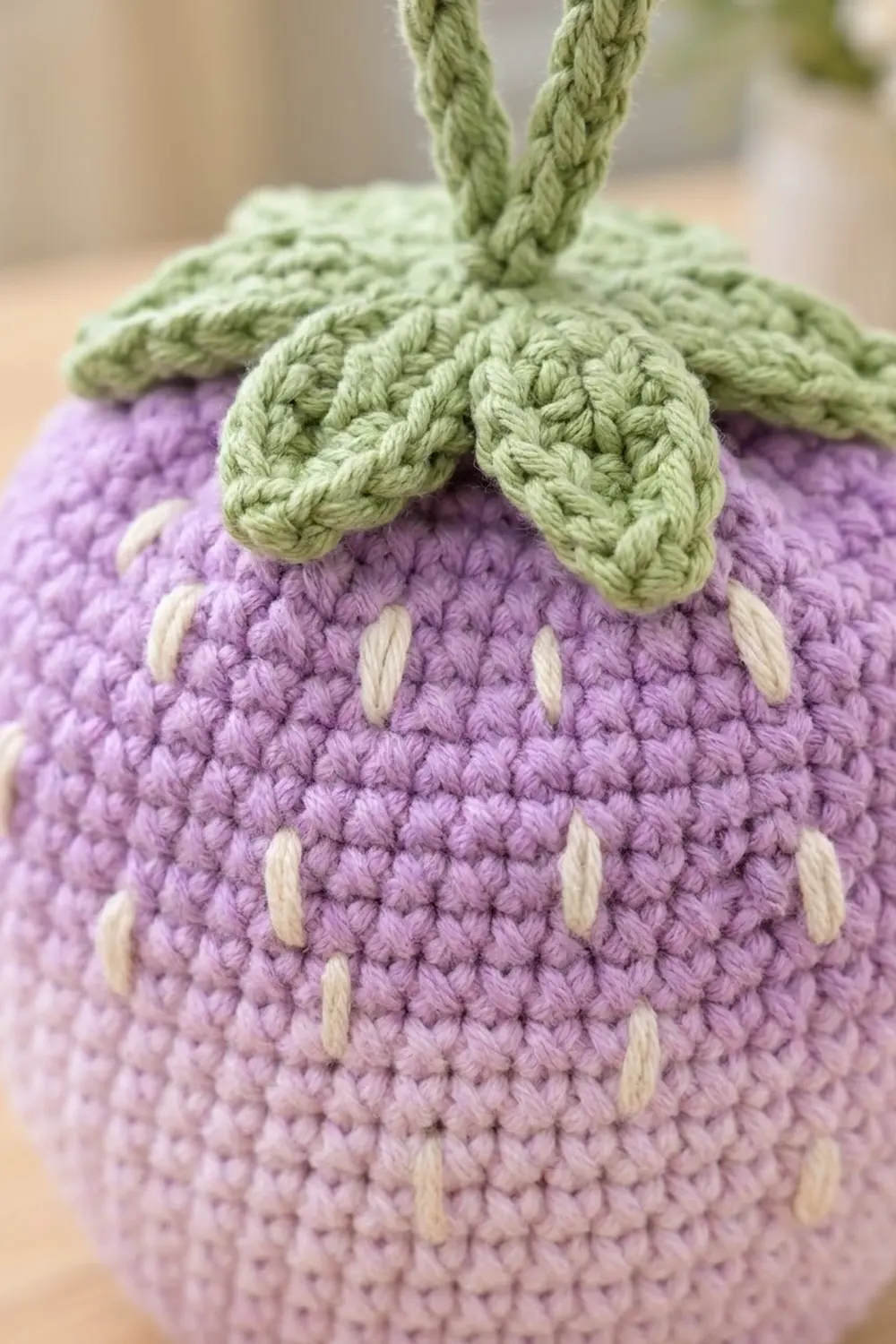 Handmade crochet amigurumi in lavender with cream seed details and green twisted leaf stem.