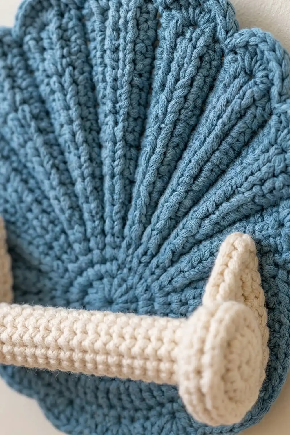 Textured cable-stitch crocheted fabric in slate blue with cream wooden button and rope toggle detail.