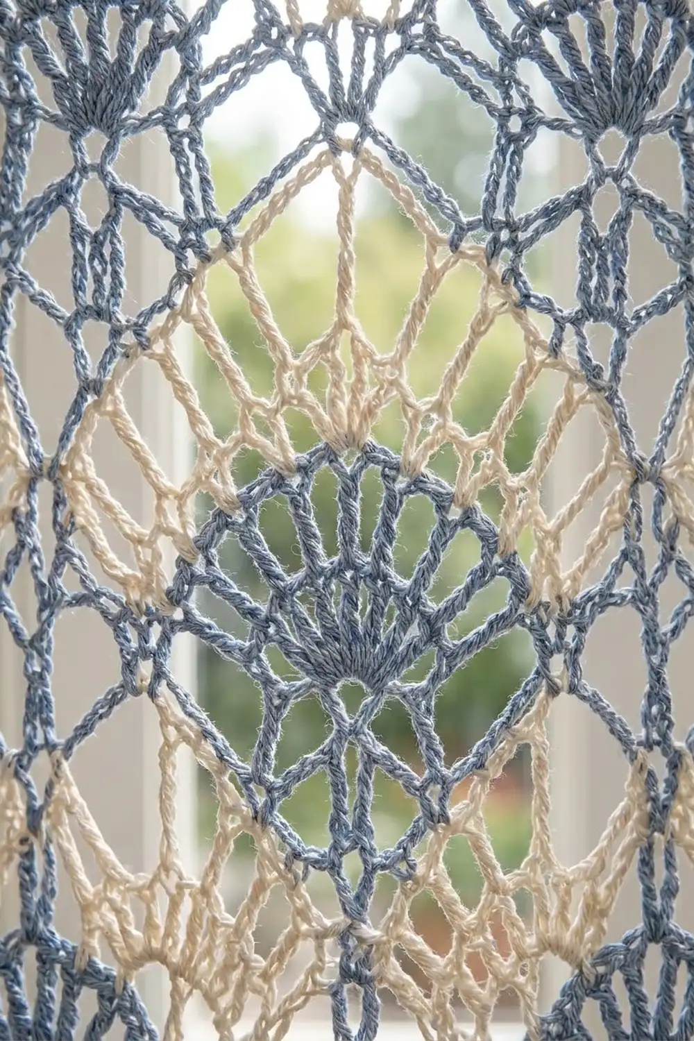 Close-up of handmade macramé wall hanging featuring knotted navy blue and cream-colored rope in geometric diamond patterns.