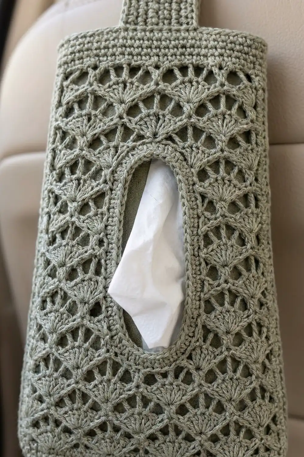 Sage green crocheted sweater with delicate lace fan-stitch pattern and white tissue visible through openings.