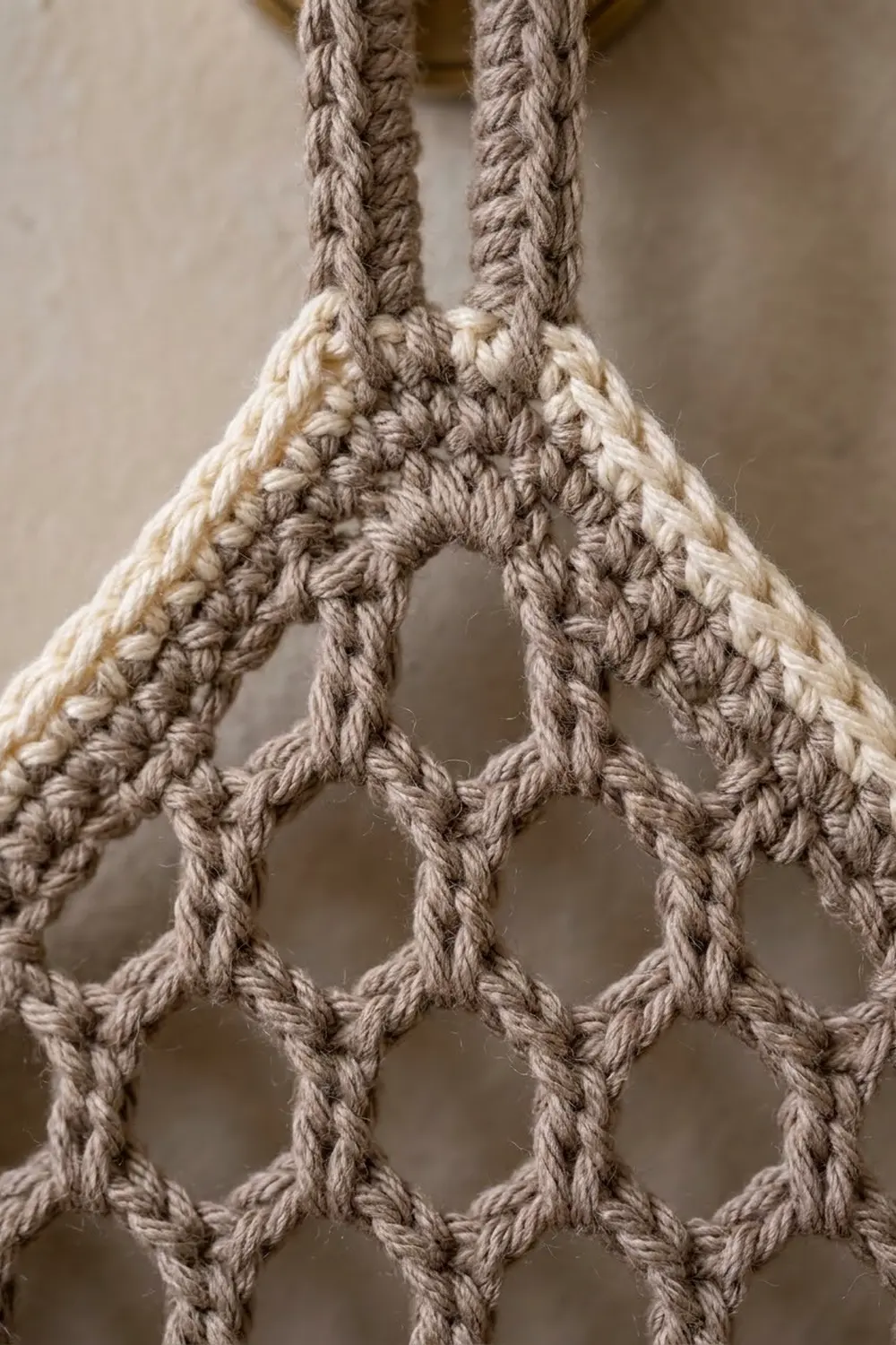 Cream and gray crocheted mesh bag shows open diamond lattice pattern with dual handles.