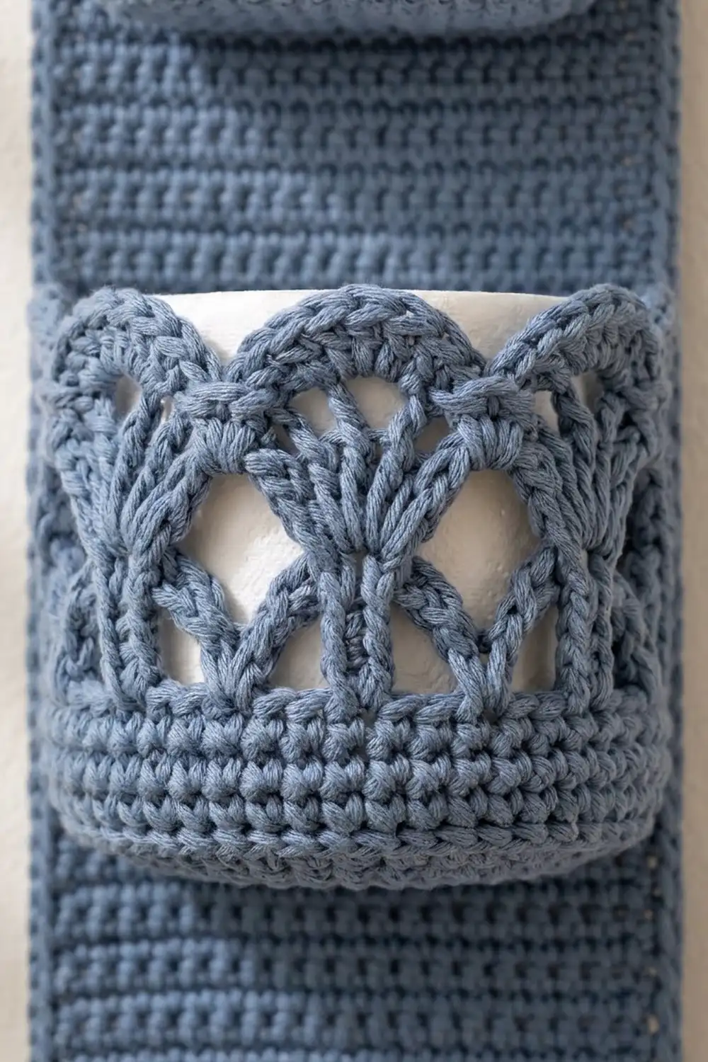 Muted blue-grey crocheted fabric with symmetrical butterfly-shaped cutout motifs and textured stitching detail.