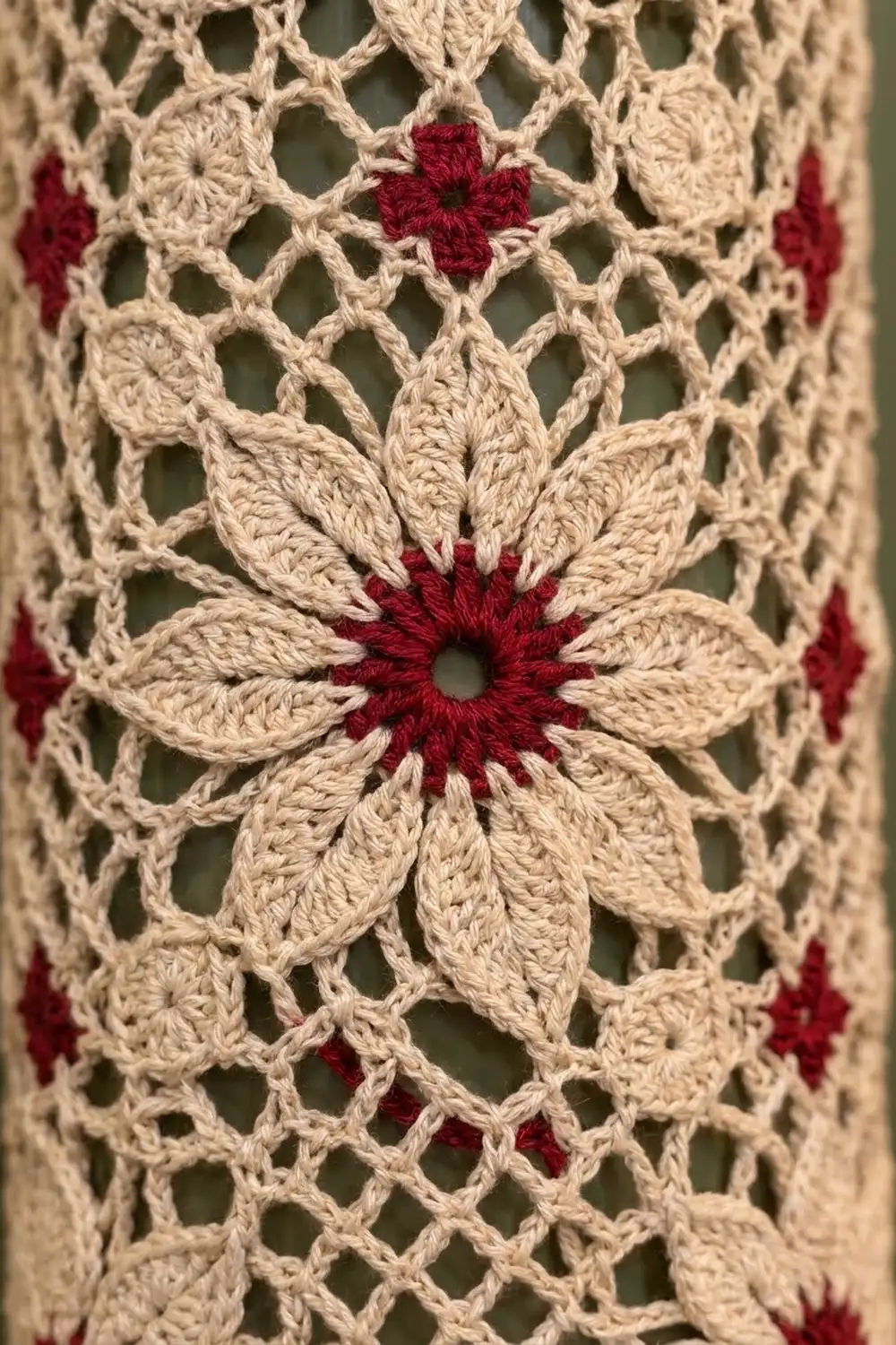 Cream crocheted lace features interlocking burgundy flowers with deep red centers in an open-work pattern.