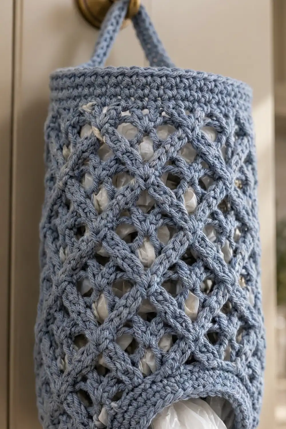 Light blue crocheted tote with open lace diamond pattern and handles against a neutral beige background.