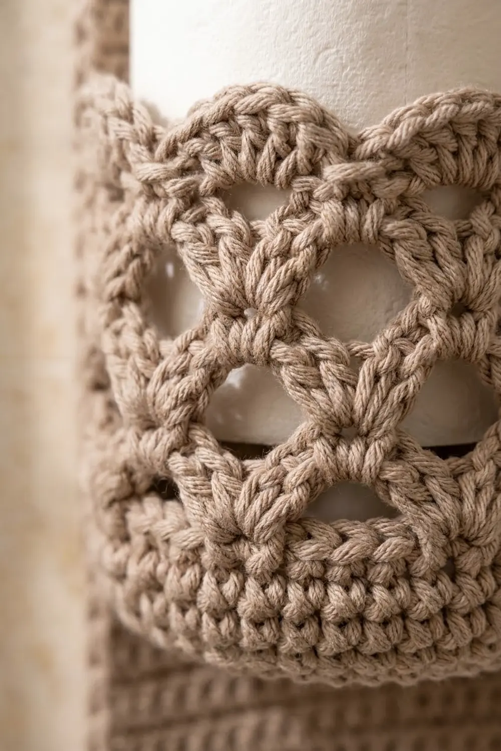 Close-up of cream crochet showing openwork stitch pattern with dimensional yarn texture against a white background.