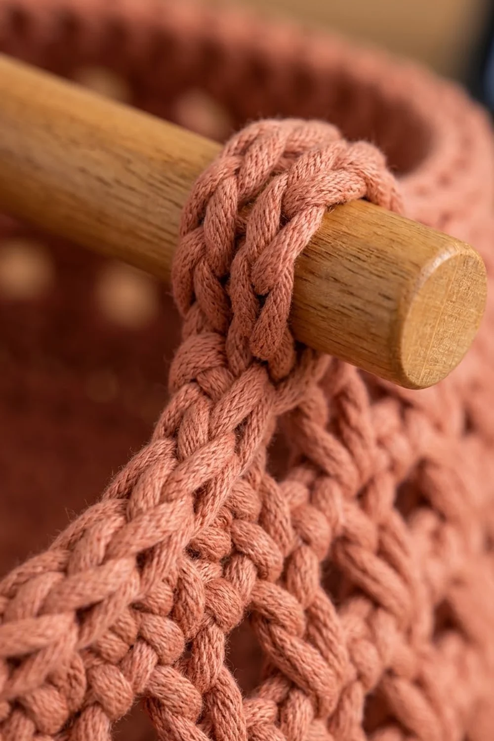 Mauve braided cord wrapped around a natural wood dowel, detailed close-up of a textile handcraft project.