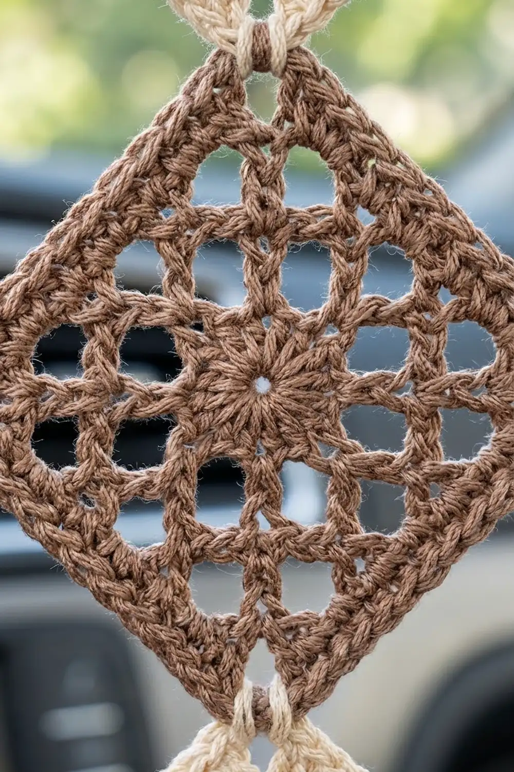 Tan macramé with intricate knotted lattice pattern and diamond-shaped openings against blurred outdoor background.