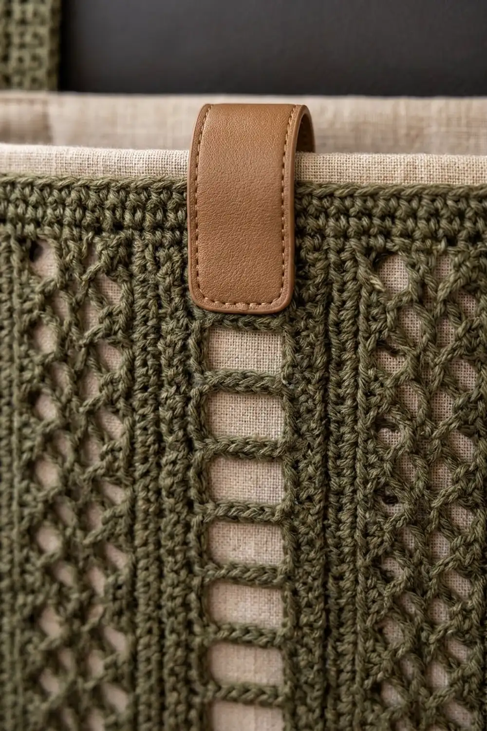 Brown leather label stitched onto textured olive-green crocheted fabric with cream-colored running stitches.