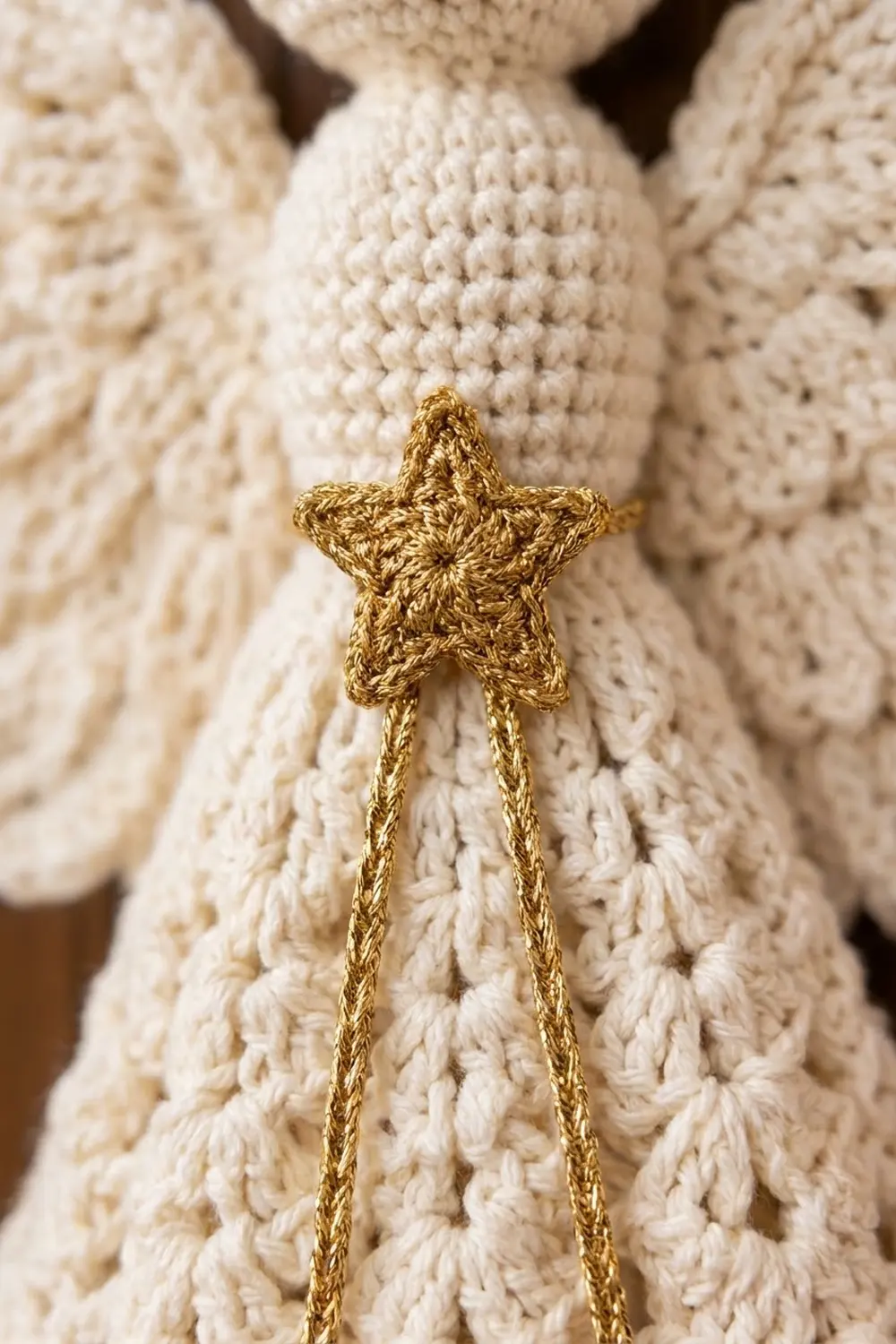 A golden crocheted star with trailing strands attached to cream-colored crochet fabric.