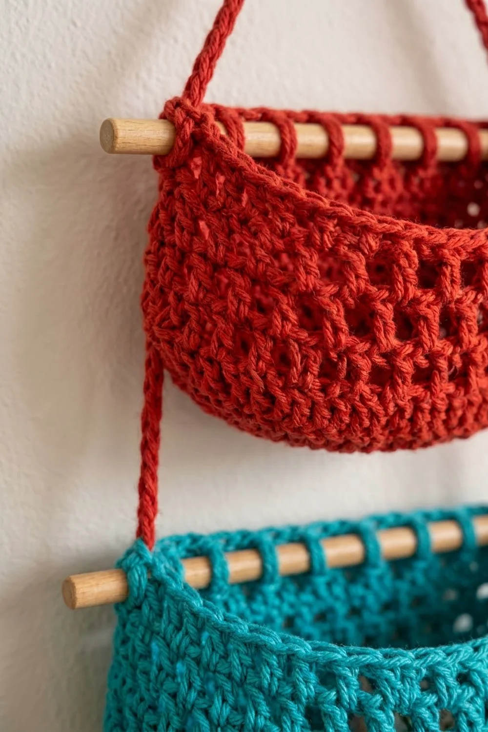 Red and teal crocheted projects with lacy openwork stitching displayed on wooden needles against a cream background.