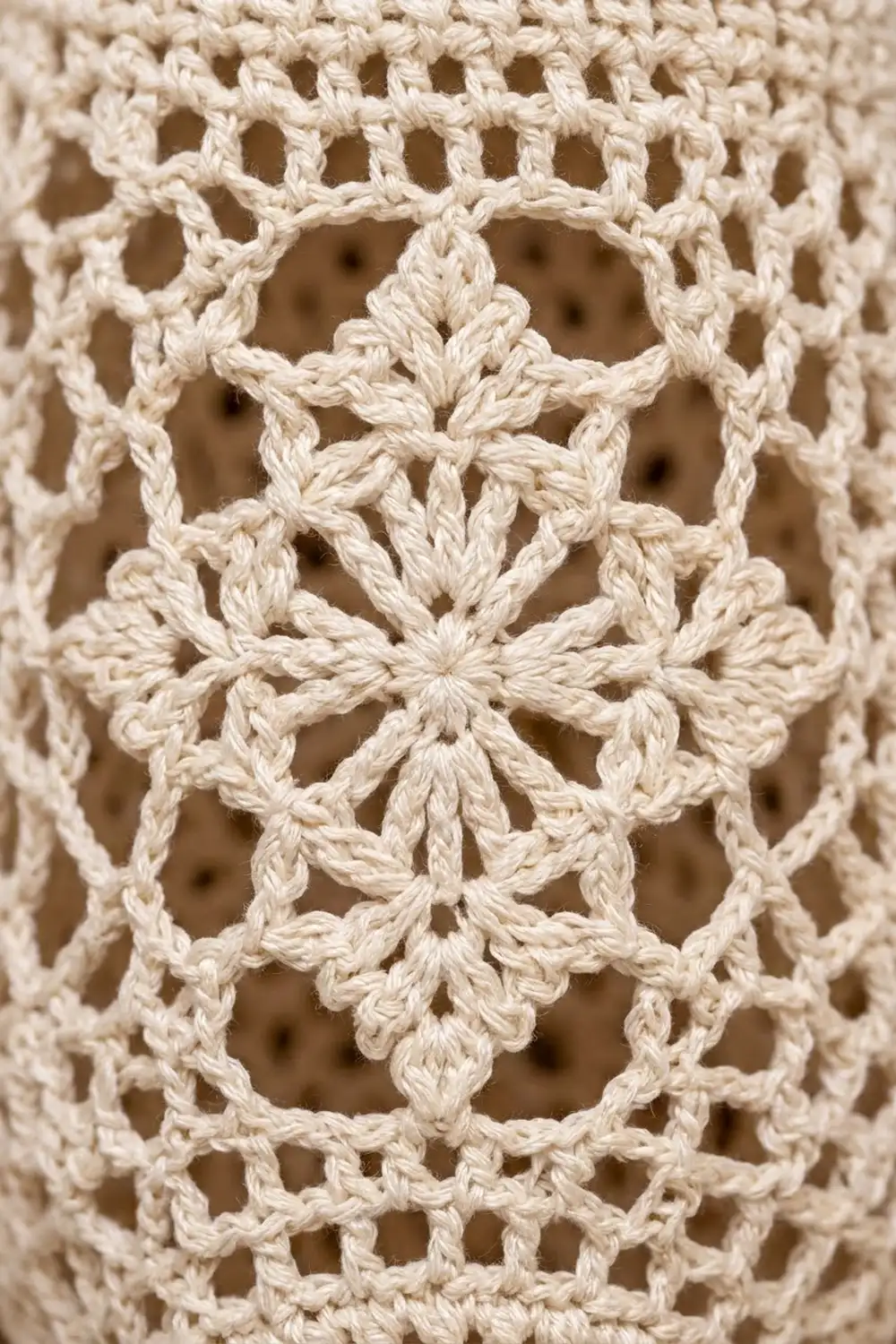 Cream-colored crocheted lace with intricate openwork pattern featuring repeating geometric star and diamond motifs.