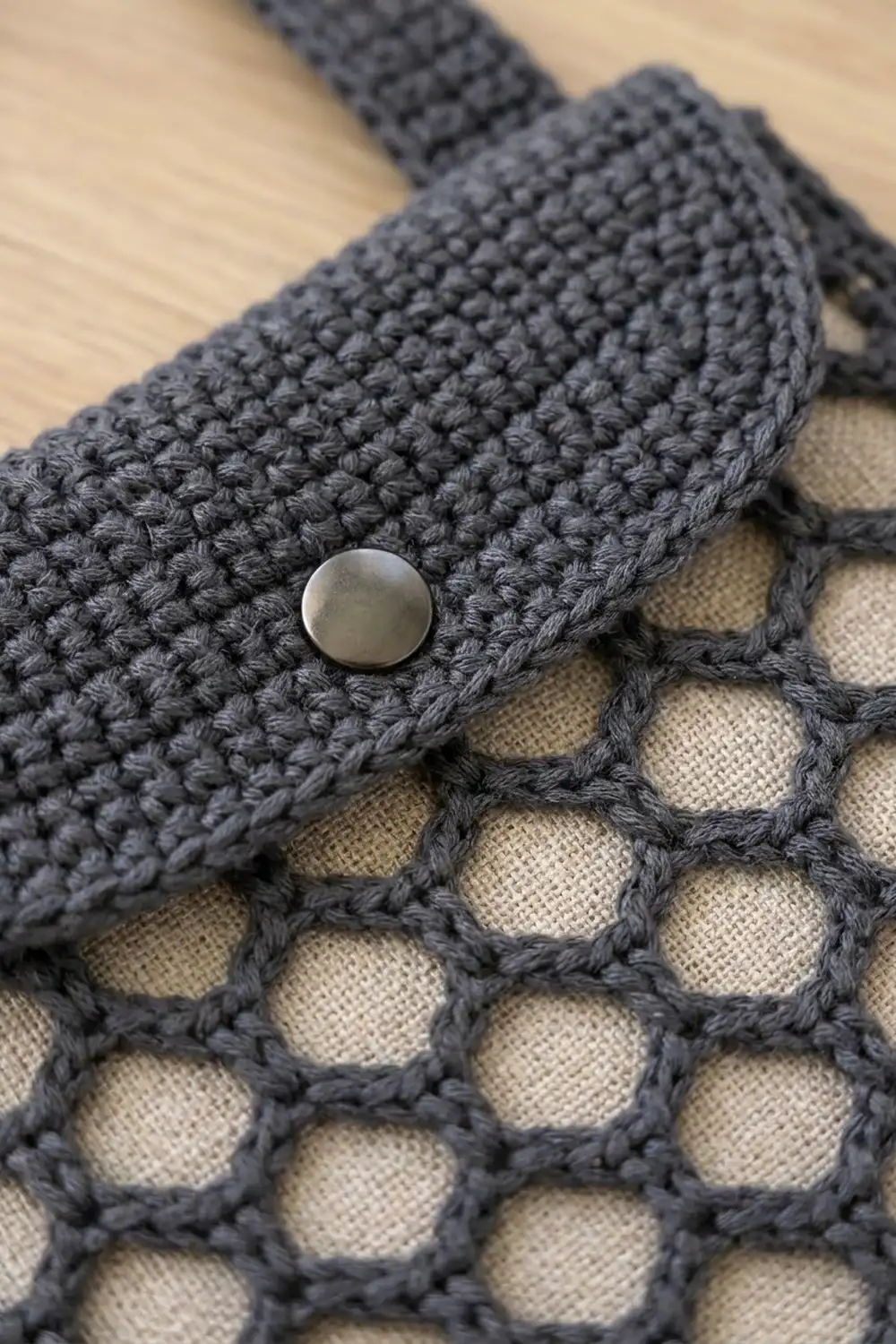 Charcoal crocheted cardigan with pearl button detail, showing textured stitching and cream linen facing.