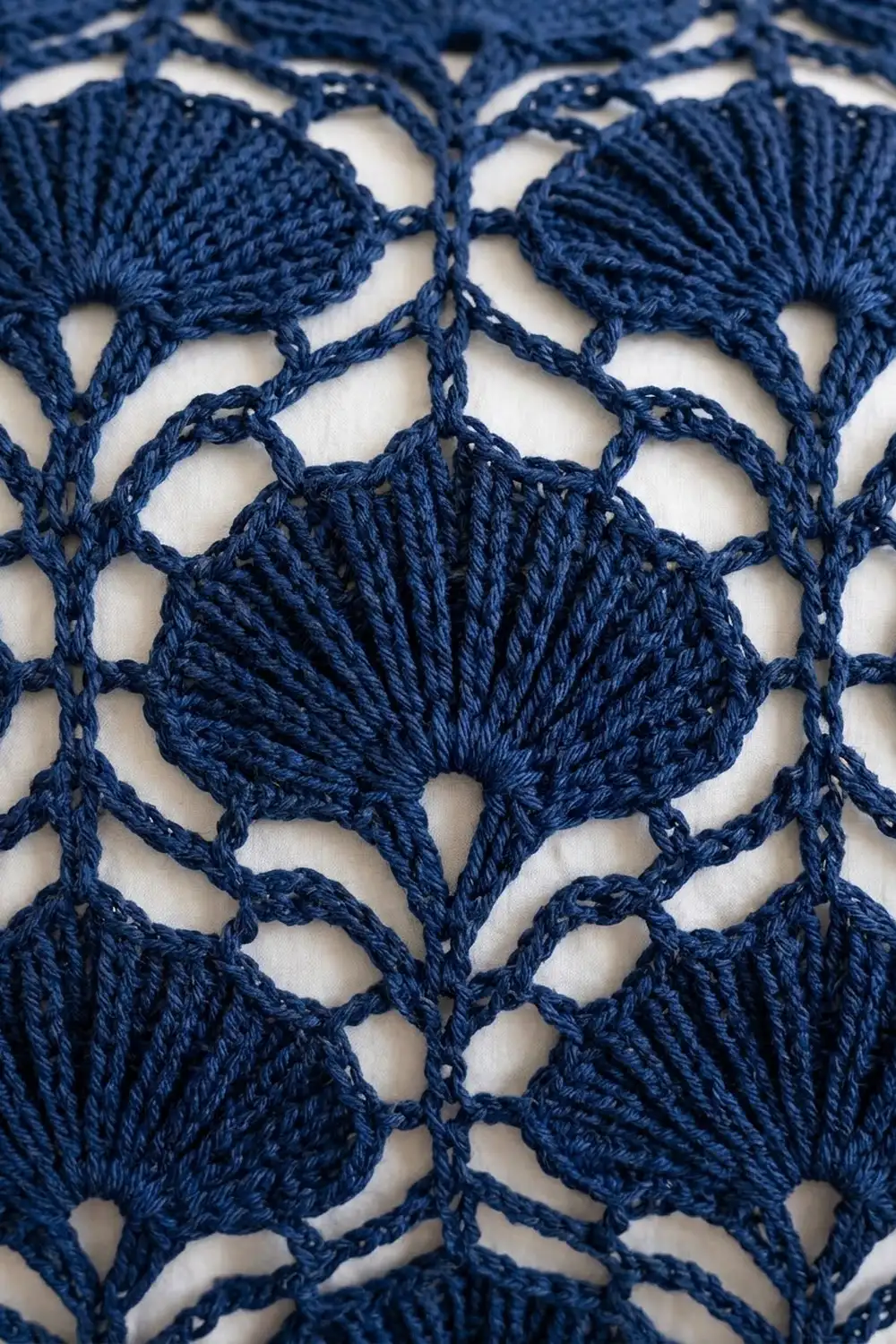 Navy blue crochet lace with geometric openwork patterns and delicate stitches displayed on a white background.