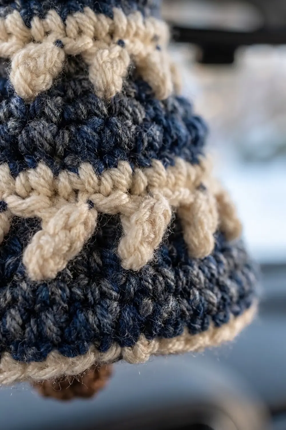 Close-up of navy and cream crocheted fabric with horizontal stripes showing textured bobble stitches.