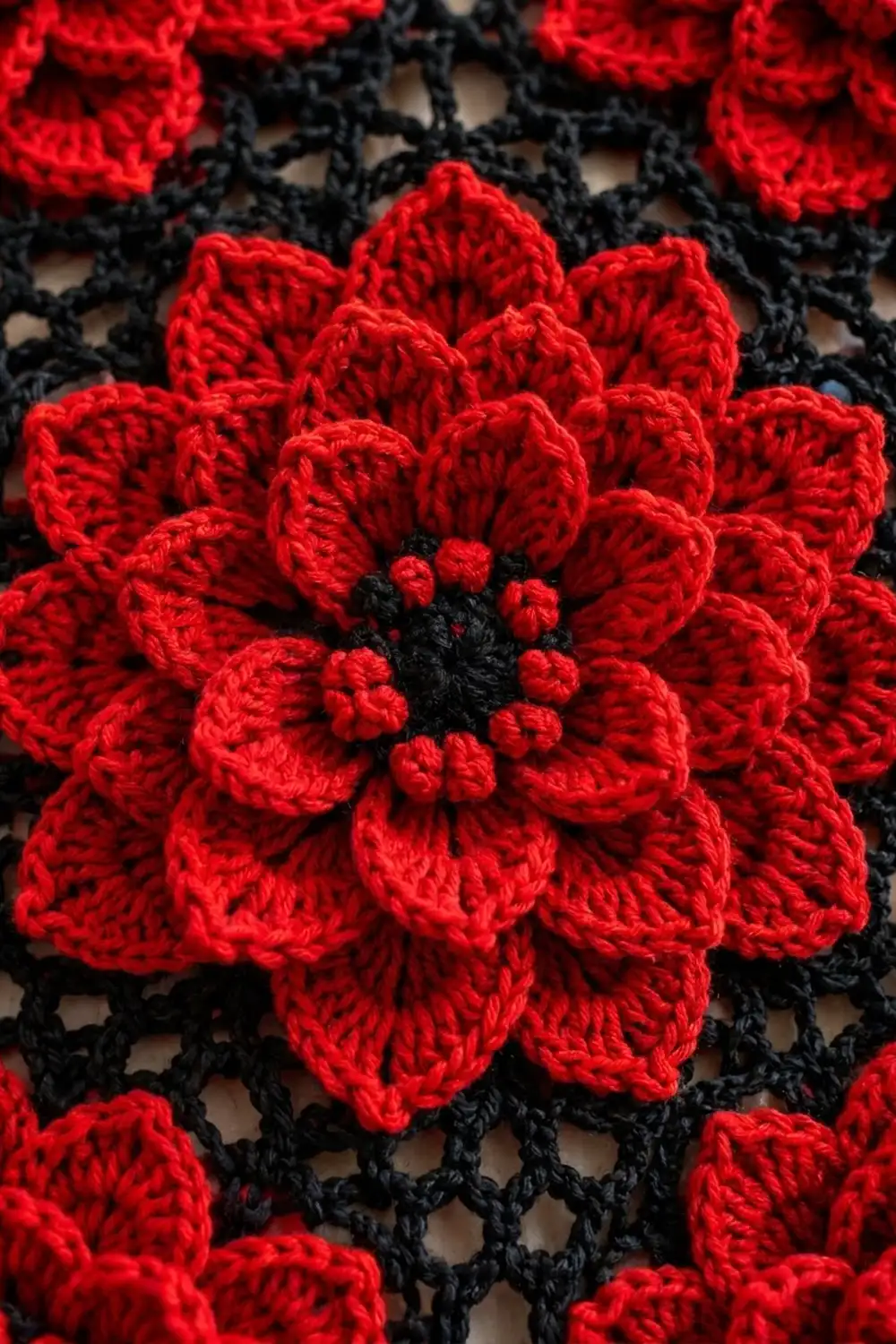 A red crocheted flower with black center details surrounded by black lace netting background.
