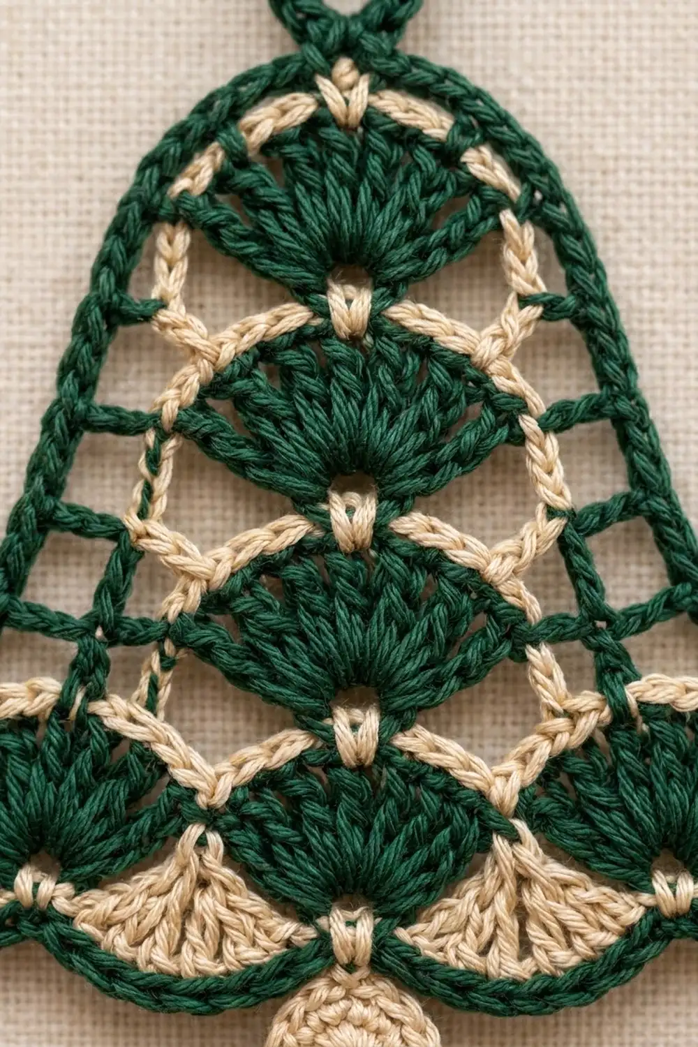 Embroidered Christmas tree ornament featuring green and cream stitched shells on linen fabric with hanging loop.