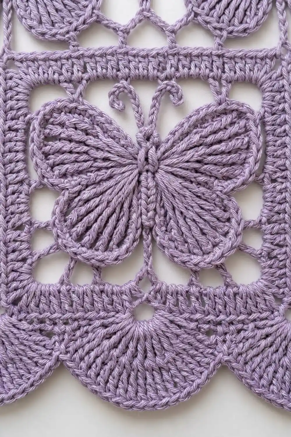 Lavender-purple crocheted lace with a detailed butterfly motif surrounded by scalloped and diamond-shaped patterns against white.