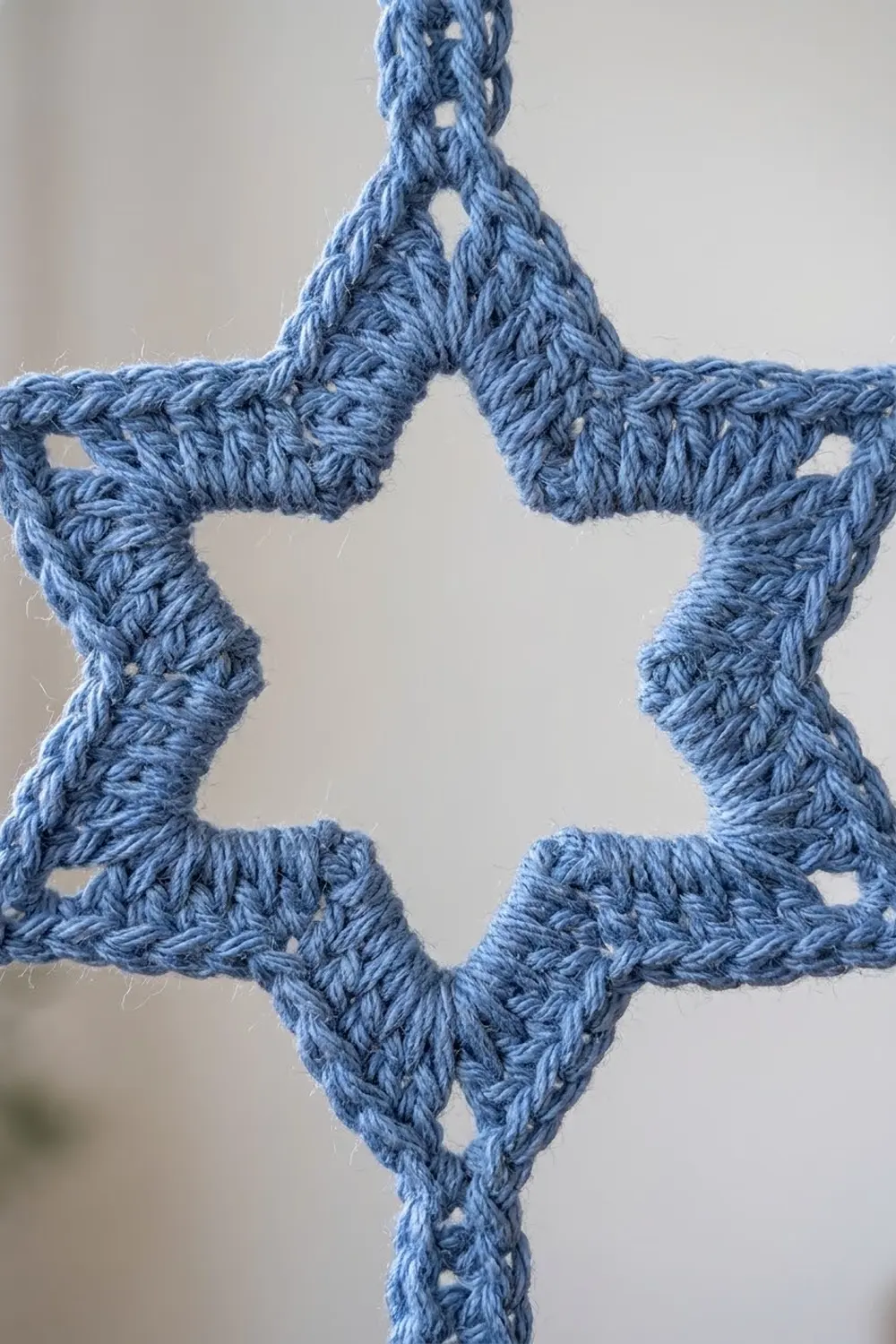 Blue crochet lace with an intricate diamond-shaped openwork pattern photographed against a neutral background.