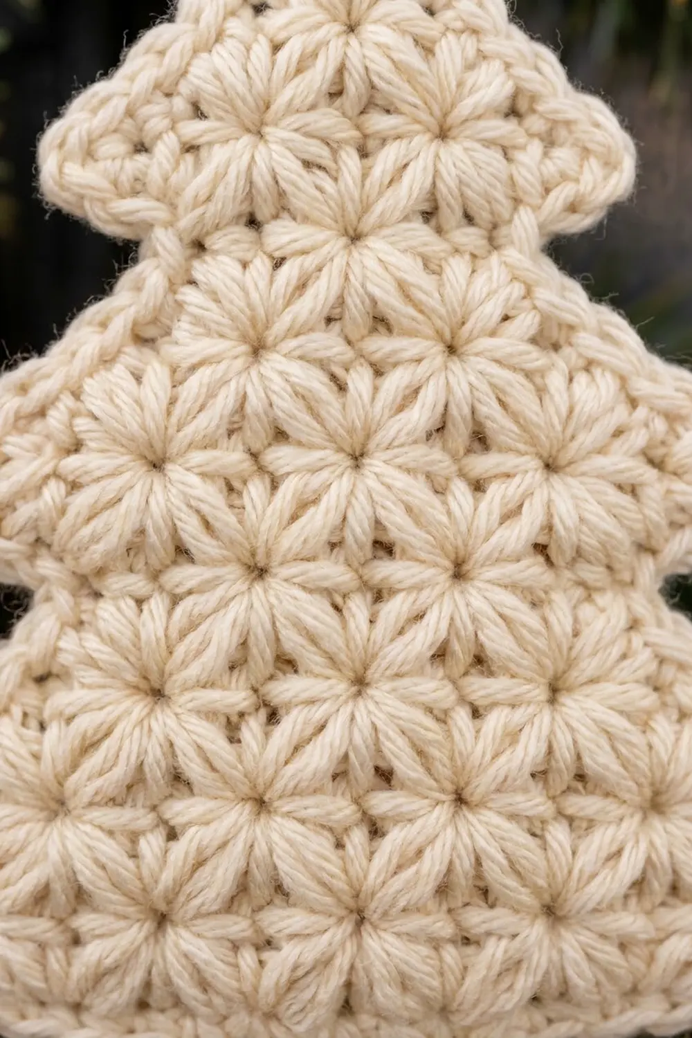 Cream-colored crochet with popcorn stitch pattern showing textured dimensional bumps against a soft blurred natural background.