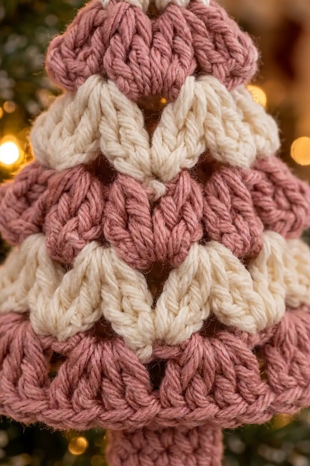 Thick striped crochet alternating dusty mauve and cream yarn with textured braided stitches and warm bokeh backdrop.