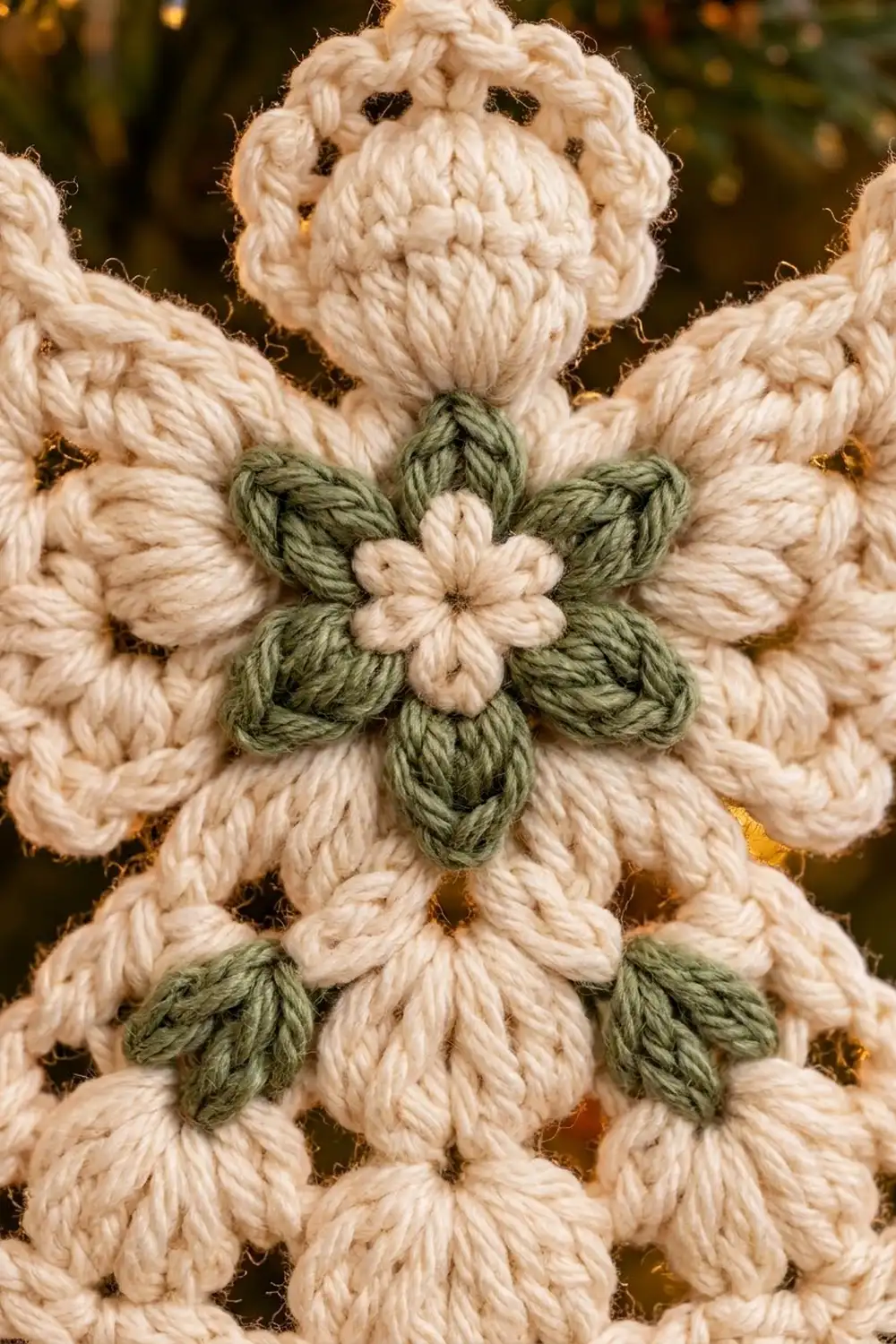 Crocheted toy with beaded eyes and a geometric green-and-cream flower design on its cream-colored body, with warm bokeh lighting behind.