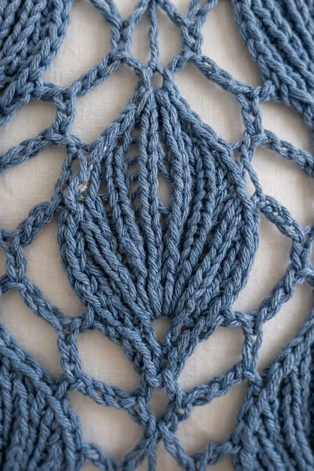 Slate-blue twisted rope macramé featuring geometric diamonds with a central bundled teardrop focal point.