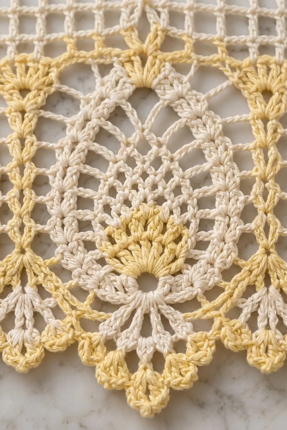 Close-up of a delicate crocheted doily featuring cream and pale yellow yarn in an intricate floral mandala pattern.