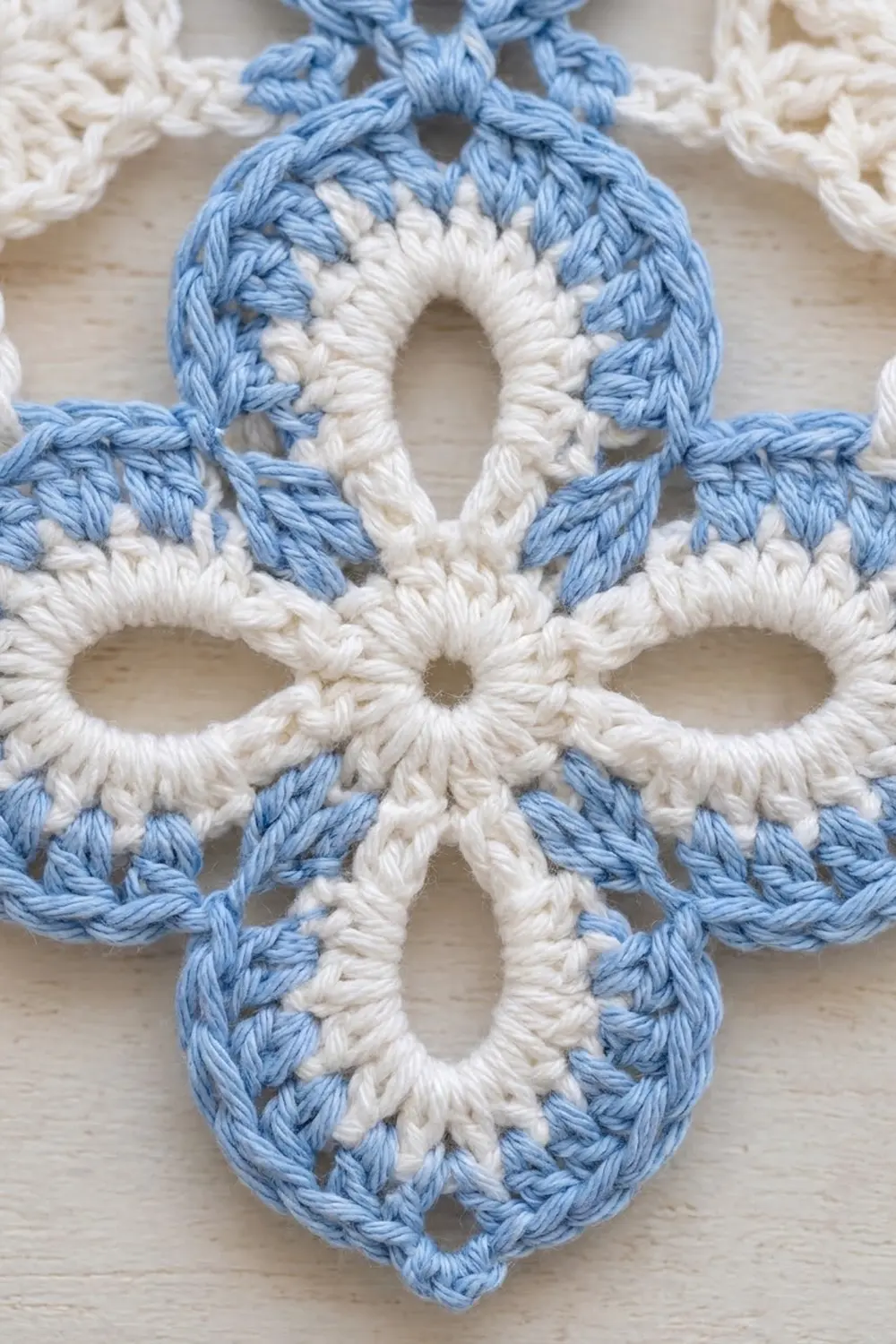 Close-up of blue and white crocheted snowflake ornament showing detailed stitching and circular pattern.
