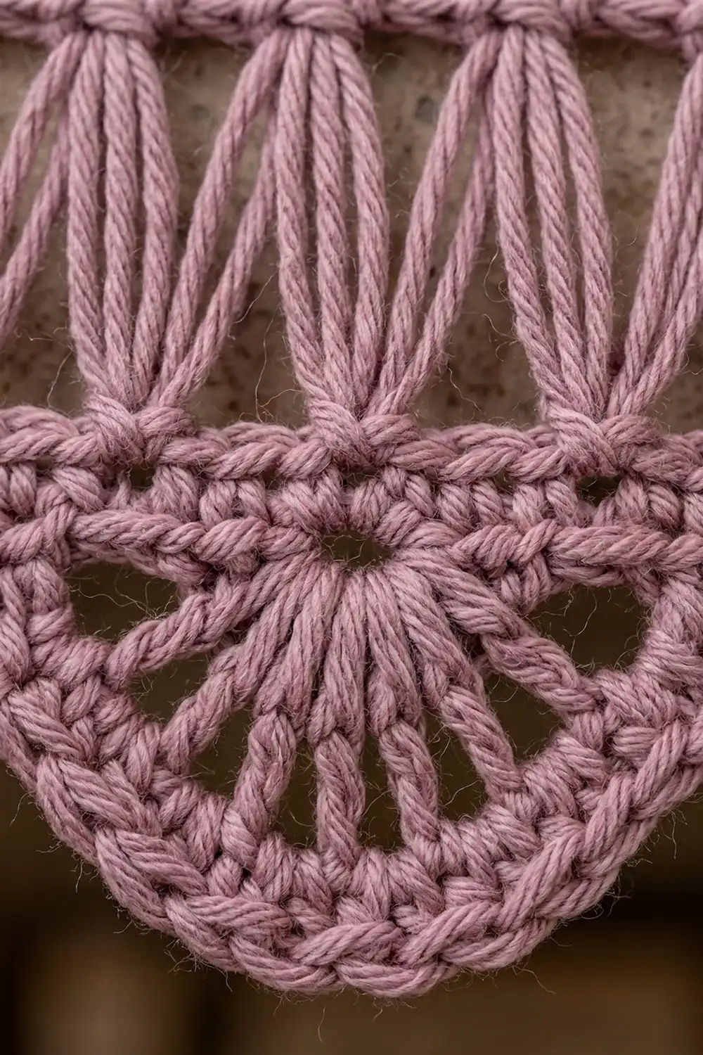 Close-up of dusty pink twisted rope with decorative knots and loops against a neutral background.