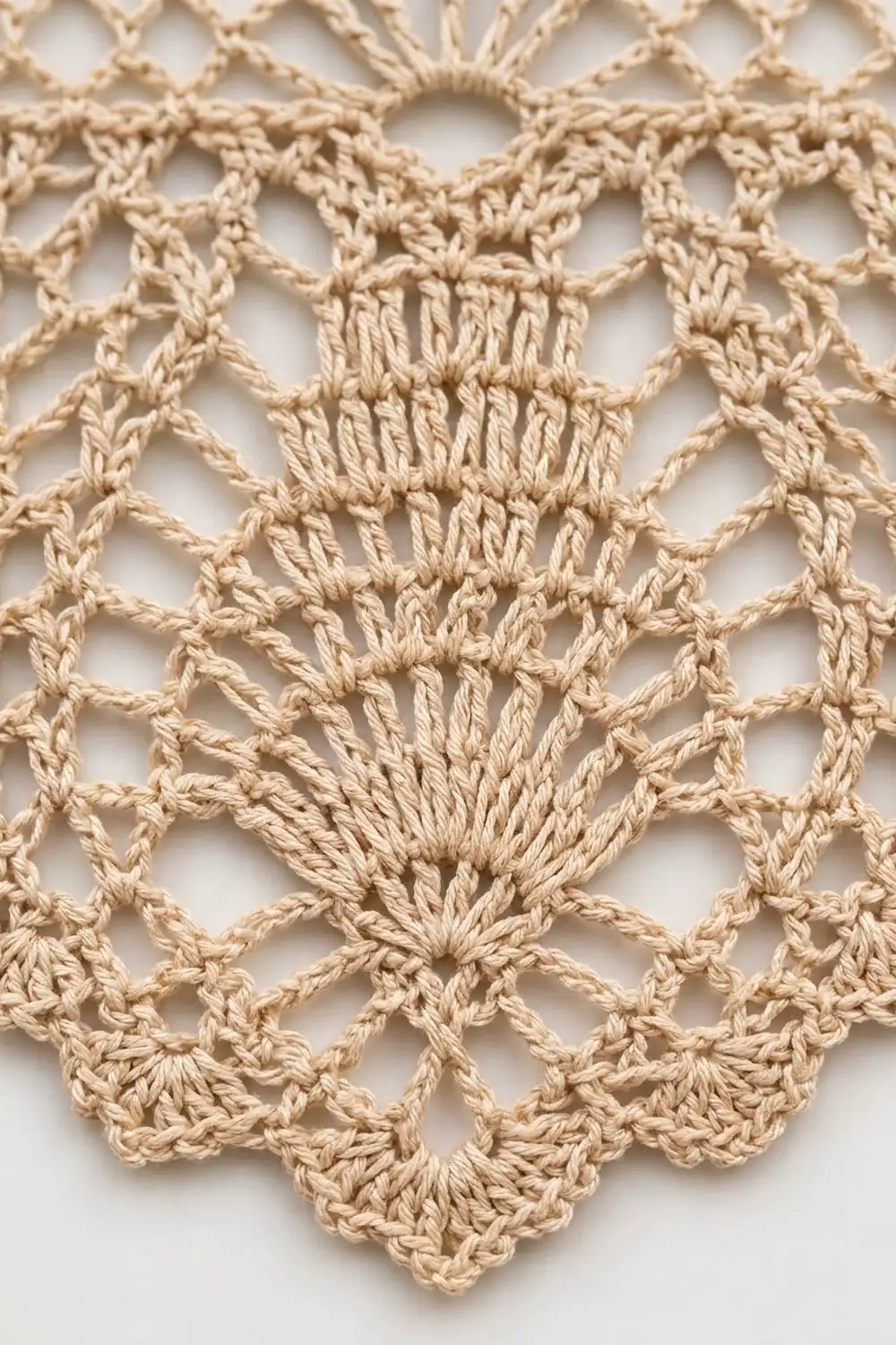 Cream-colored crocheted lace doily with intricate geometric patterns and open mesh design displayed against a white background.
