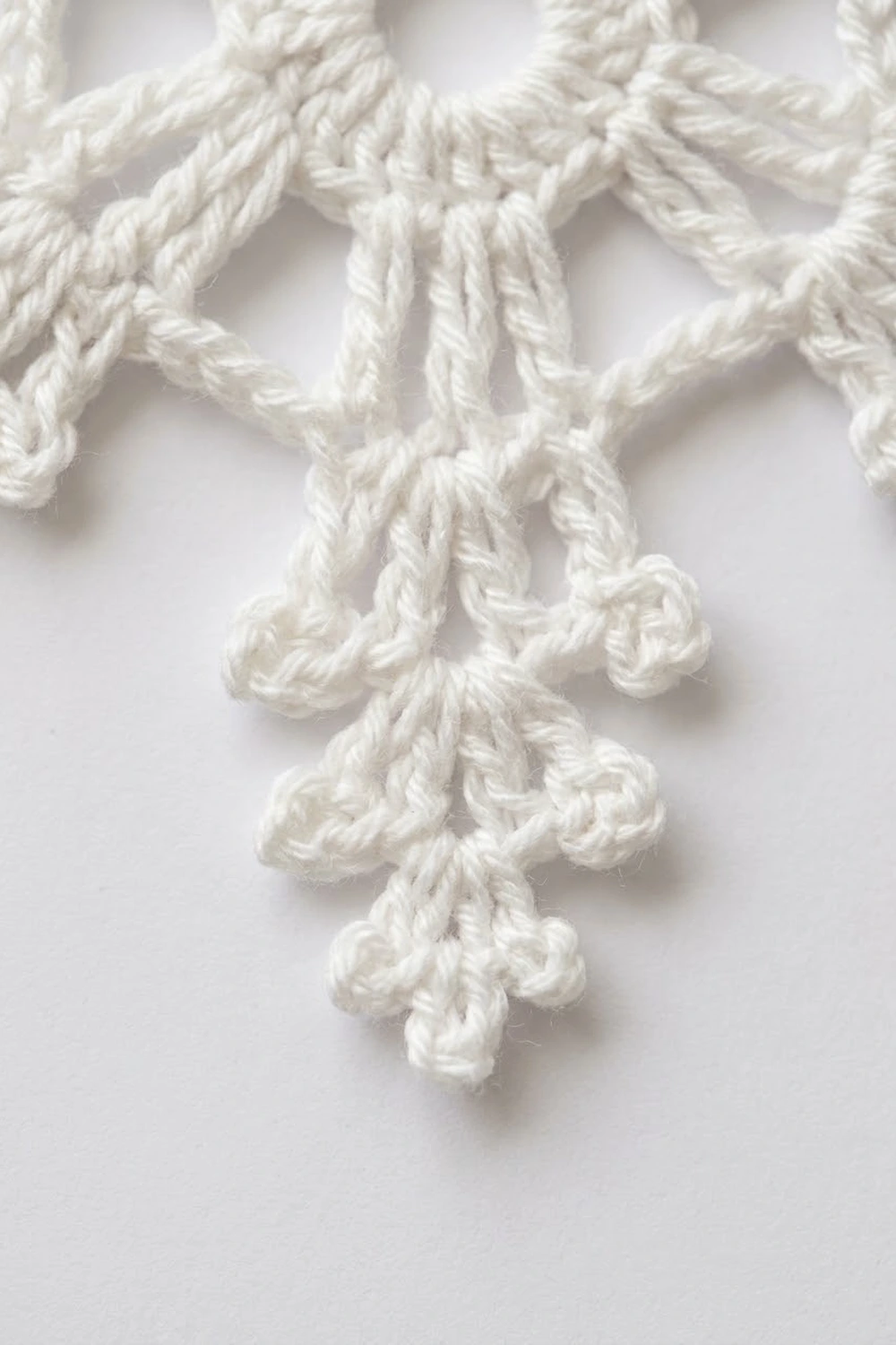 White twisted rope arranged in a decorative knot pattern against a plain light background.