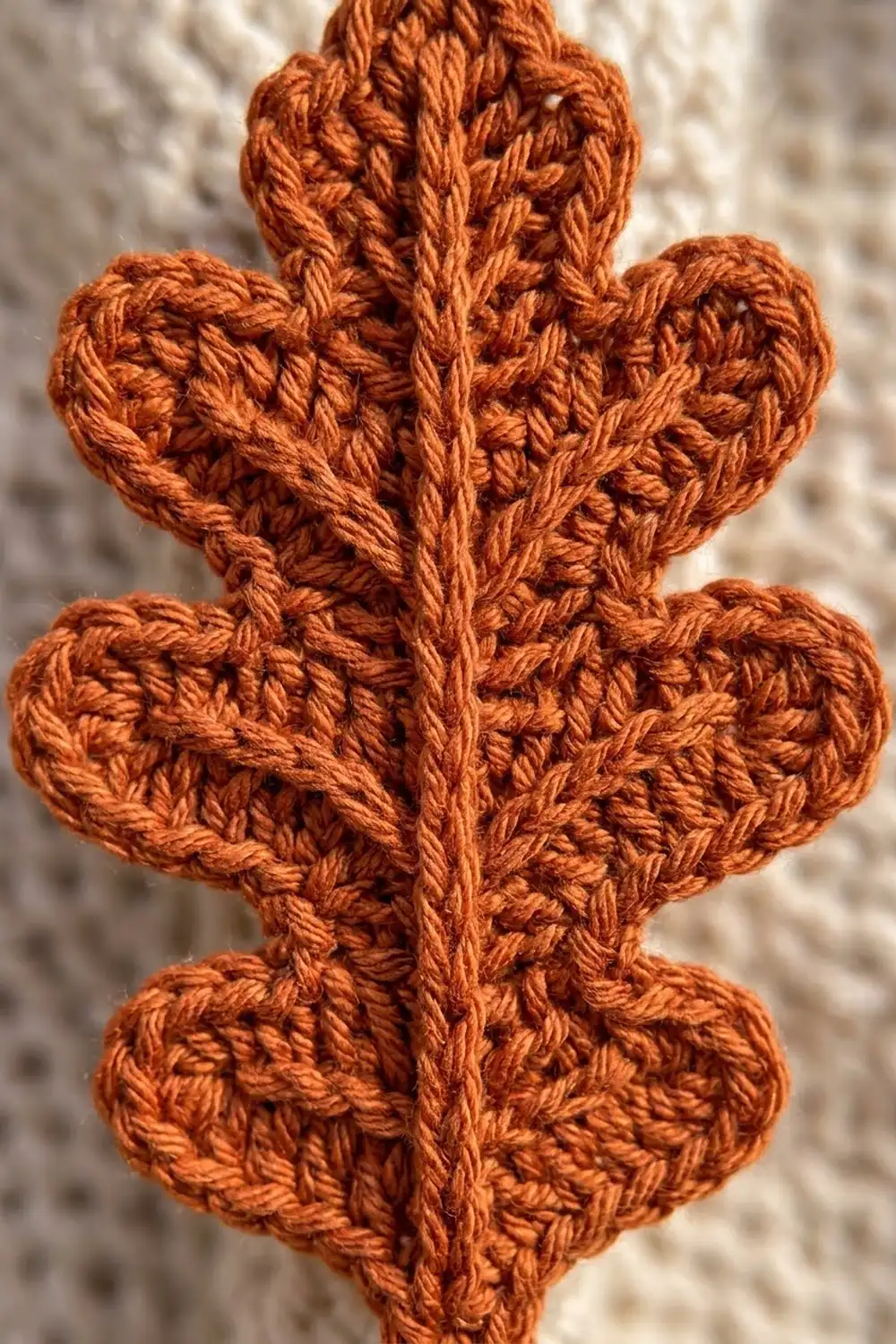 Crocheted rust-orange cactus with textured segments displayed against a light speckled background.
