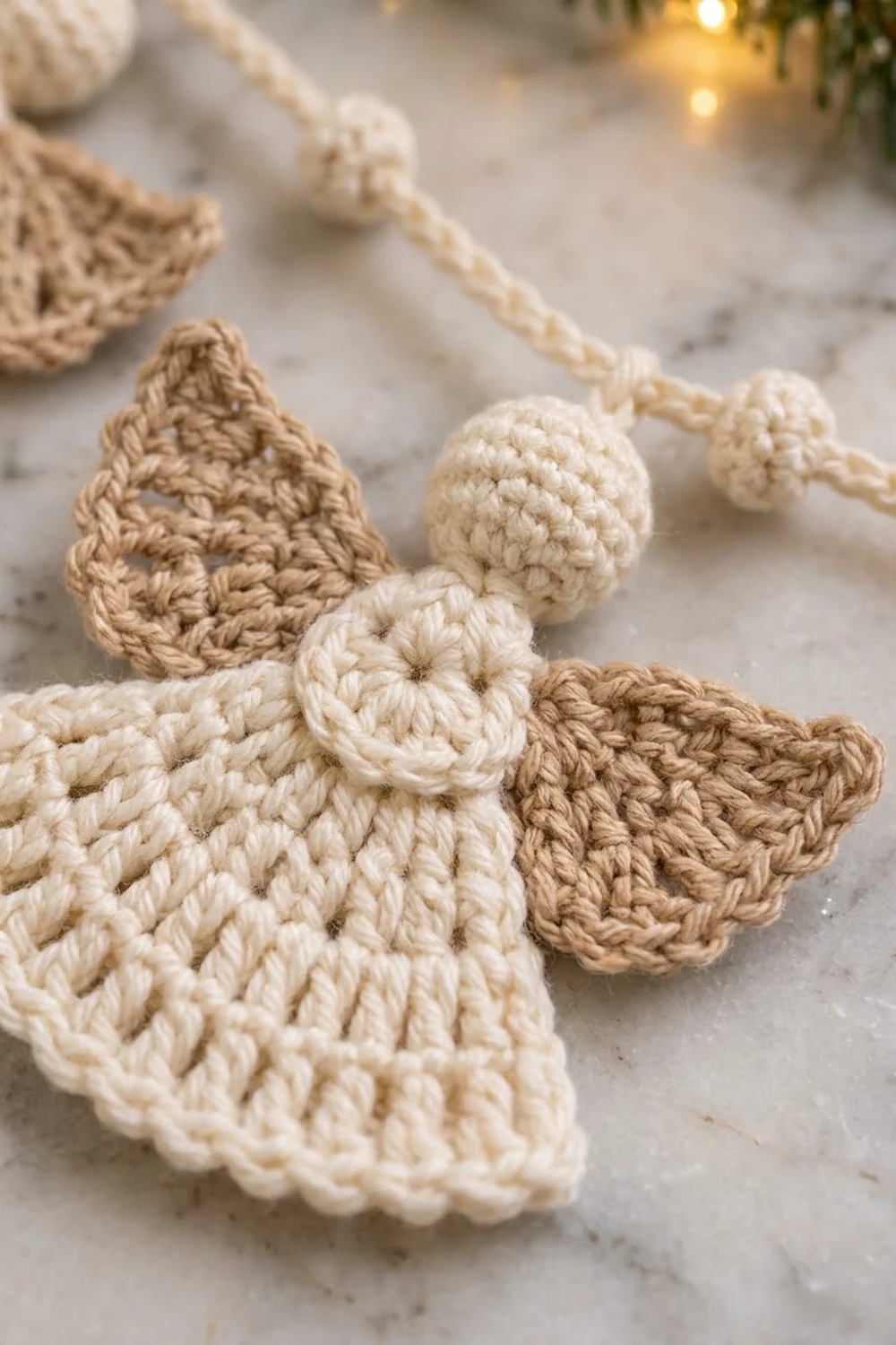 Crocheted angel ornaments in cream and tan yarn with beaded details displayed on a marble surface.