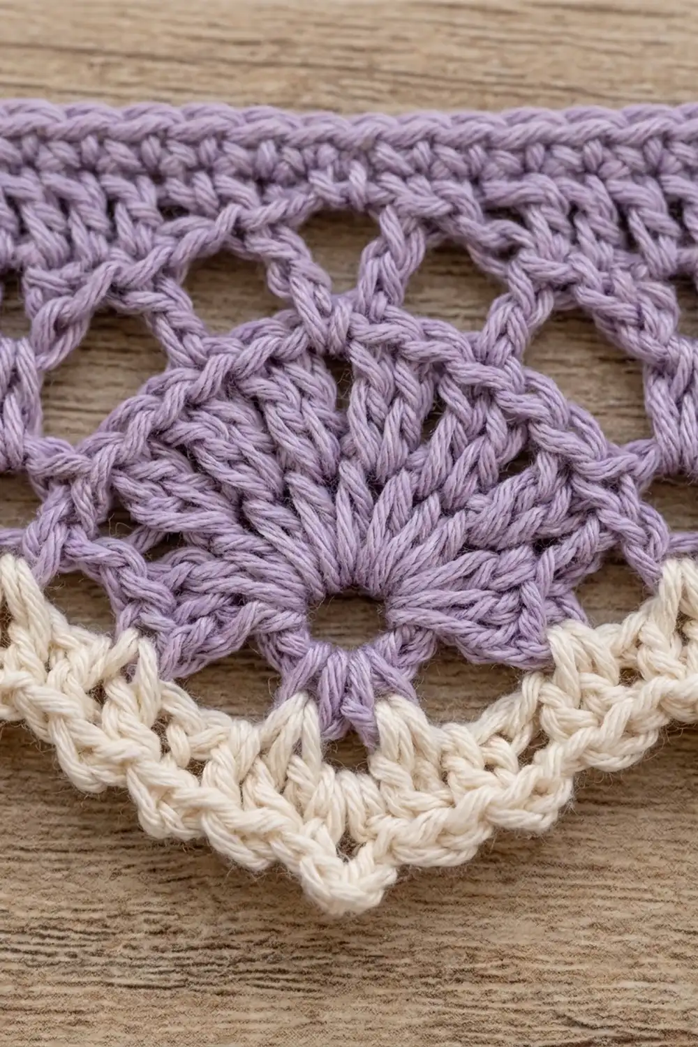 Close-up of lavender and cream crocheted lace trim with butterfly motifs on wooden surface.