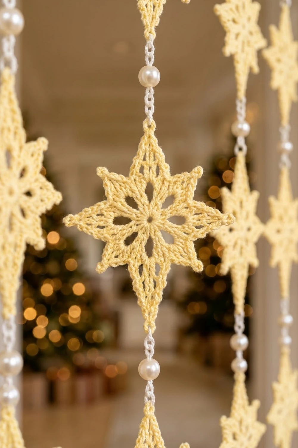 Crocheted golden snowflake ornament with pearl beads hanging from delicate chain against warm bokeh background.