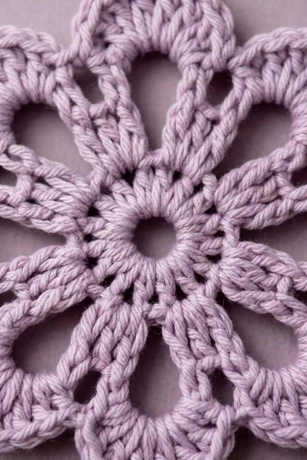 Close-up of a lavender crochet or macramé snowflake ornament with intricate knotted rope detail.