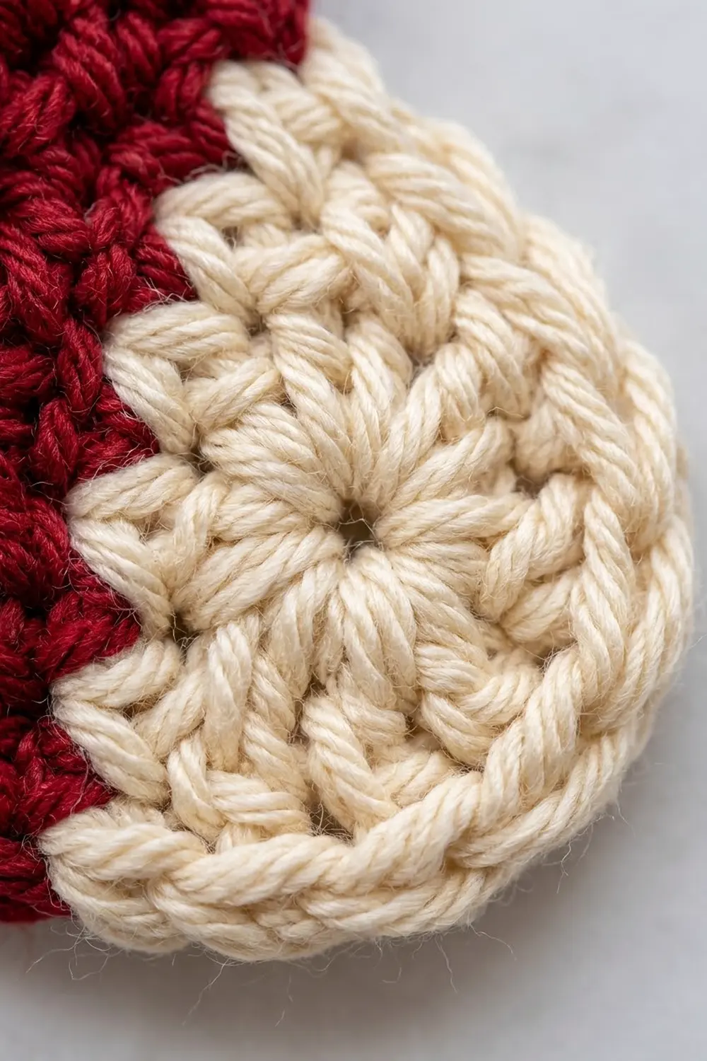 Close-up of red and cream-colored crocheted or knitted fabric showing textured stitching detail.