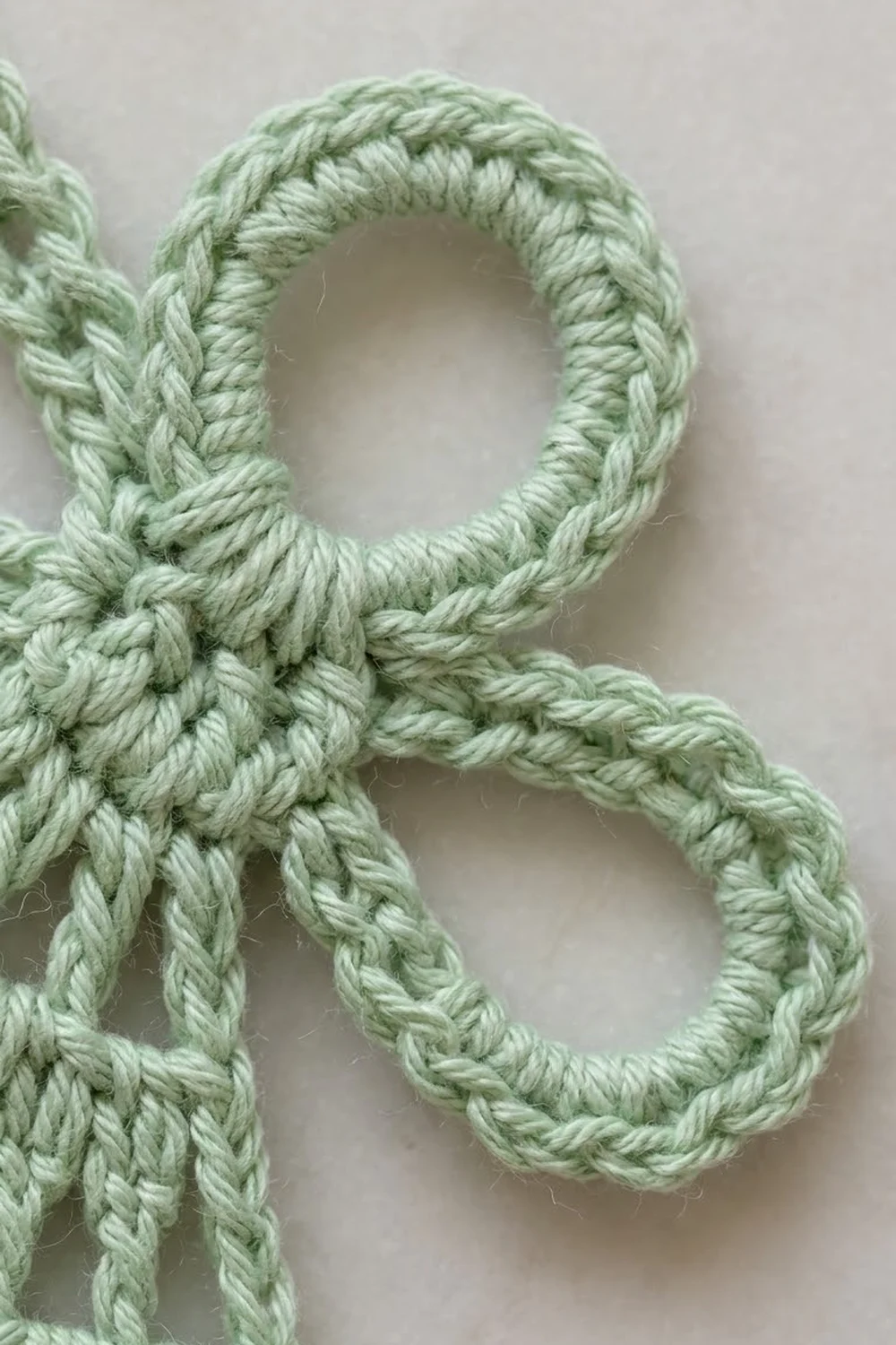 Close-up of pale green braided rope forming decorative loops against a white background.