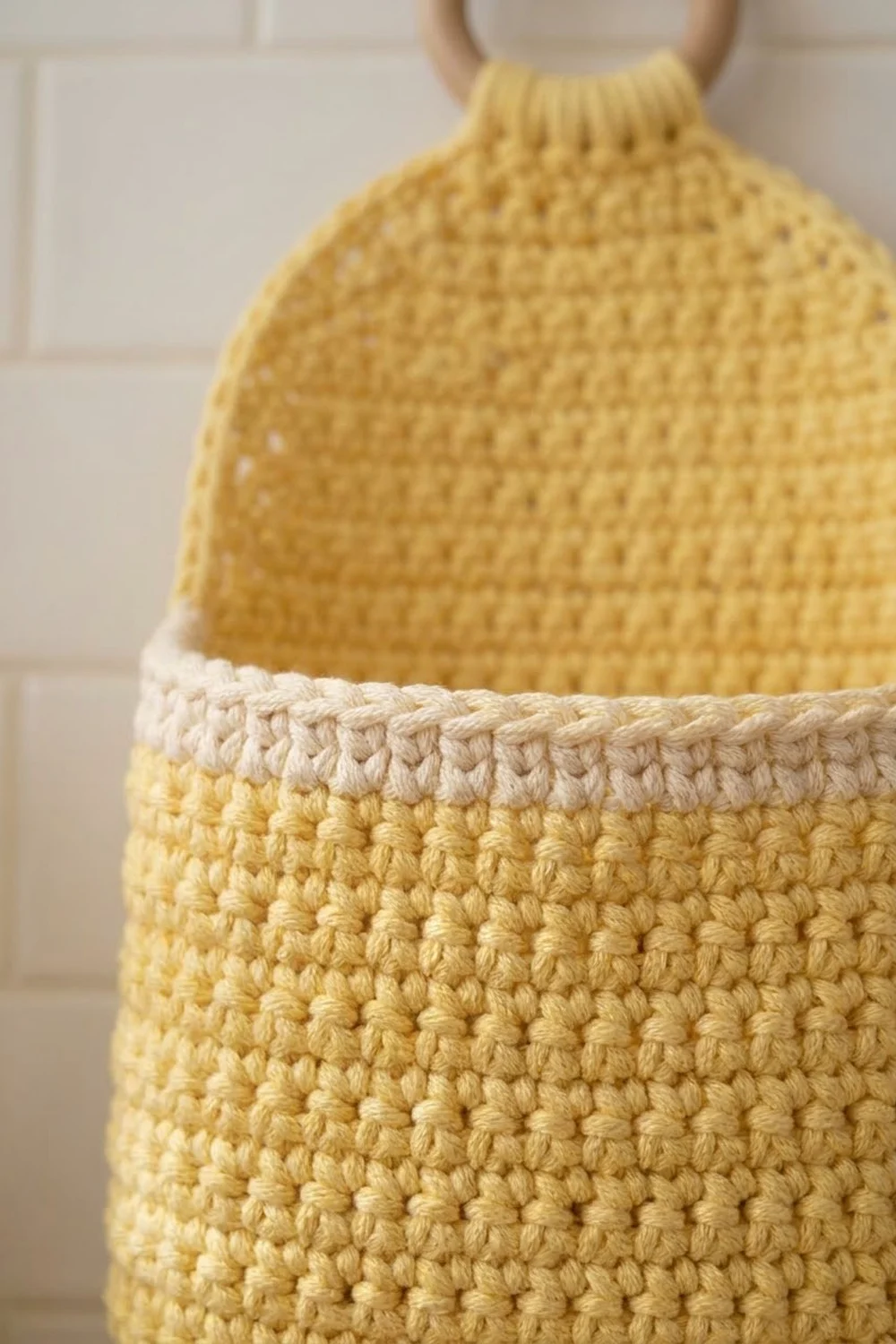 Close-up detail of a yellow and cream crocheted basket with textured stitching and rope handles.