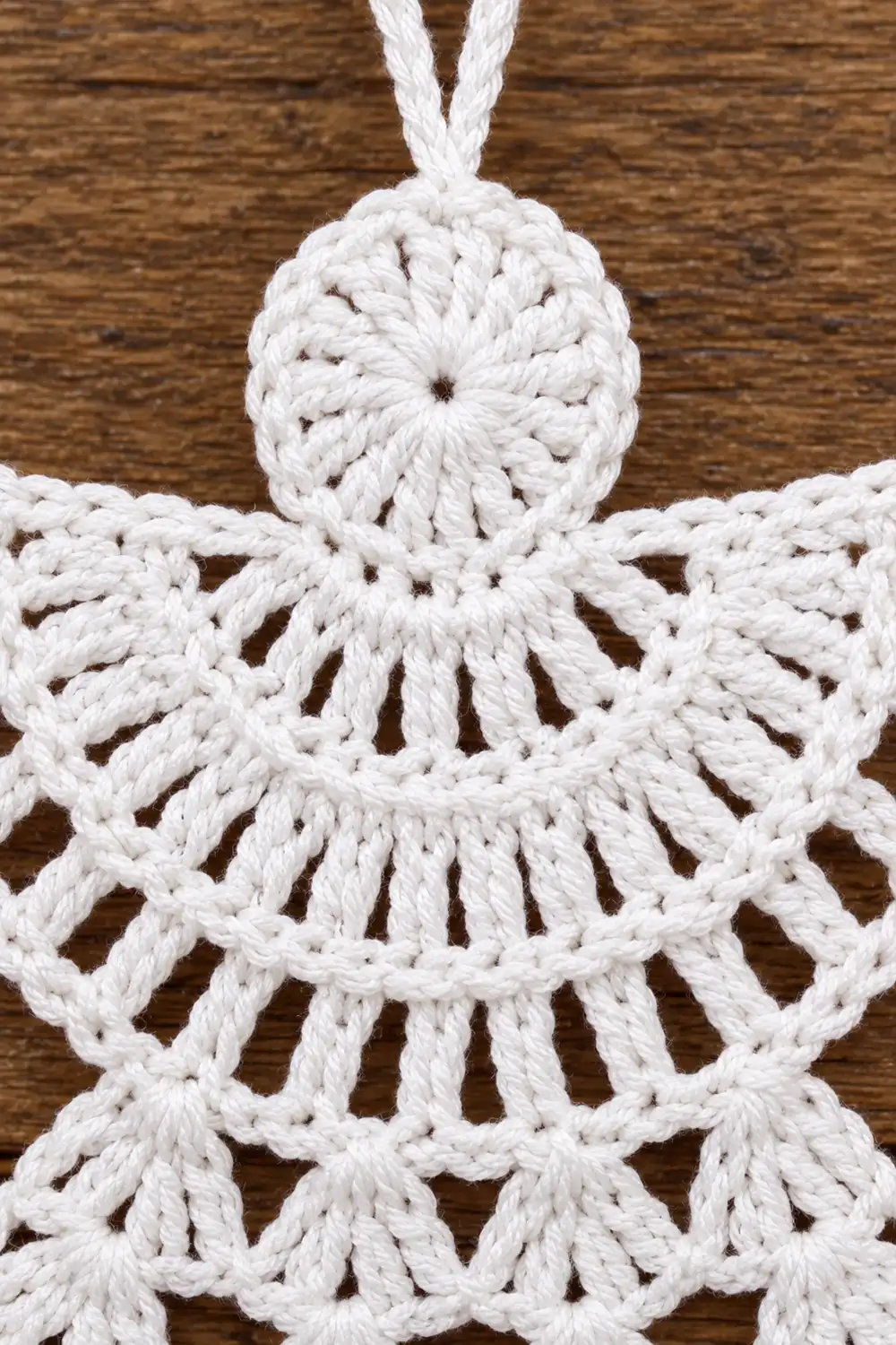White macramé star ornament with braided rope details hanging against a wooden background.
