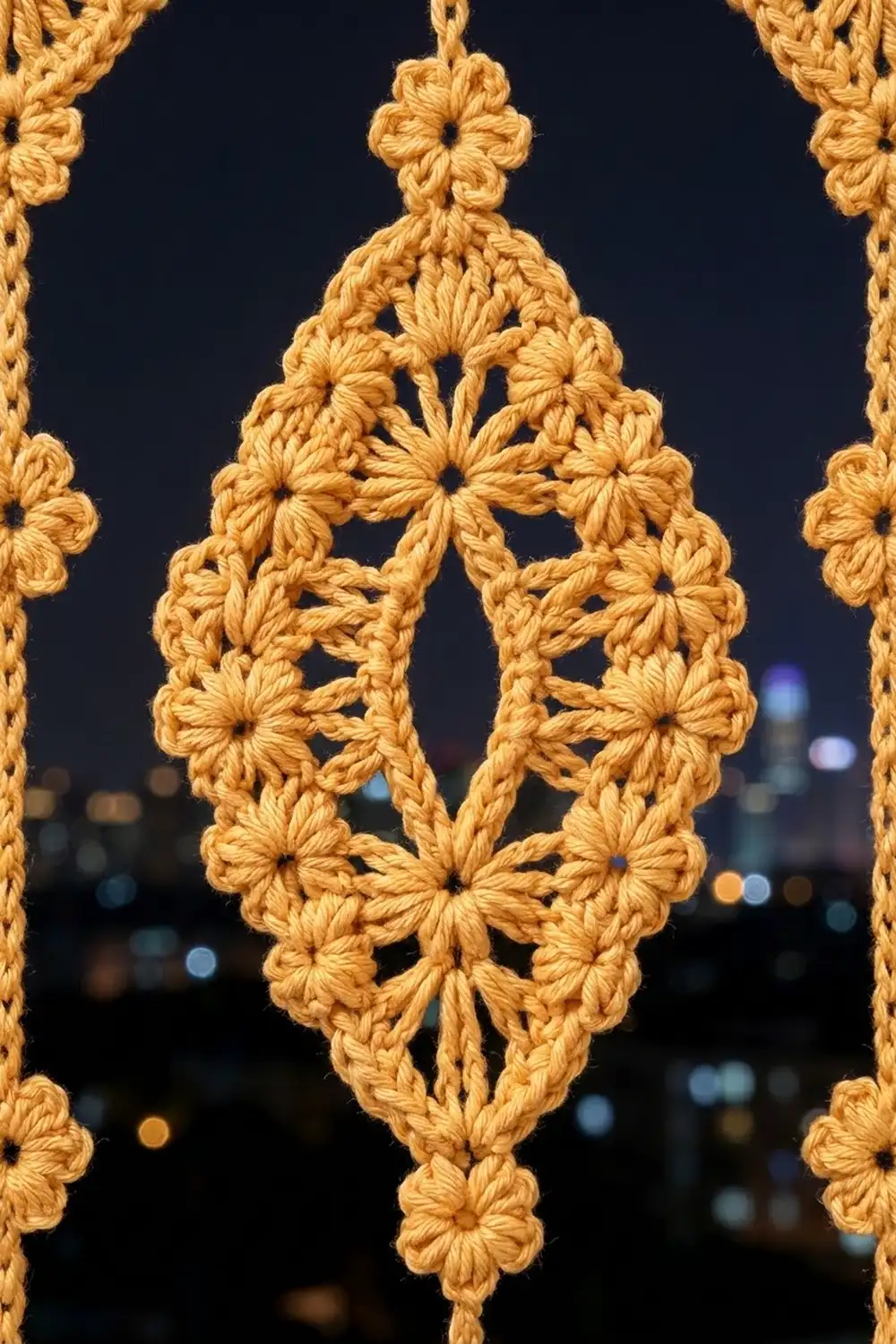 Golden crocheted flower medallions hanging against a dark night sky with blurred city lights in the background.