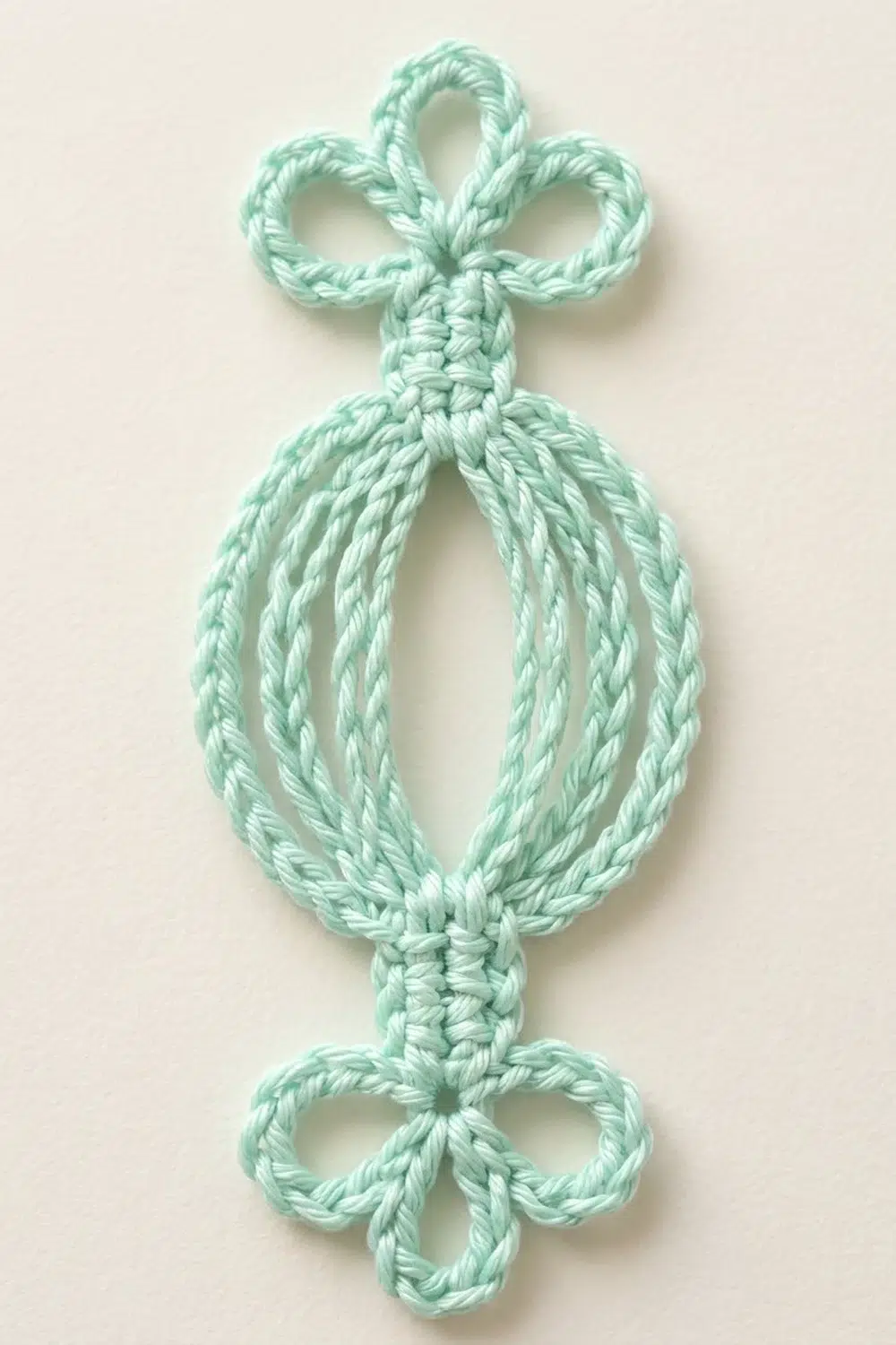 A mint green twisted rope ornament with bow loops at top and bottom, photographed against a cream background.